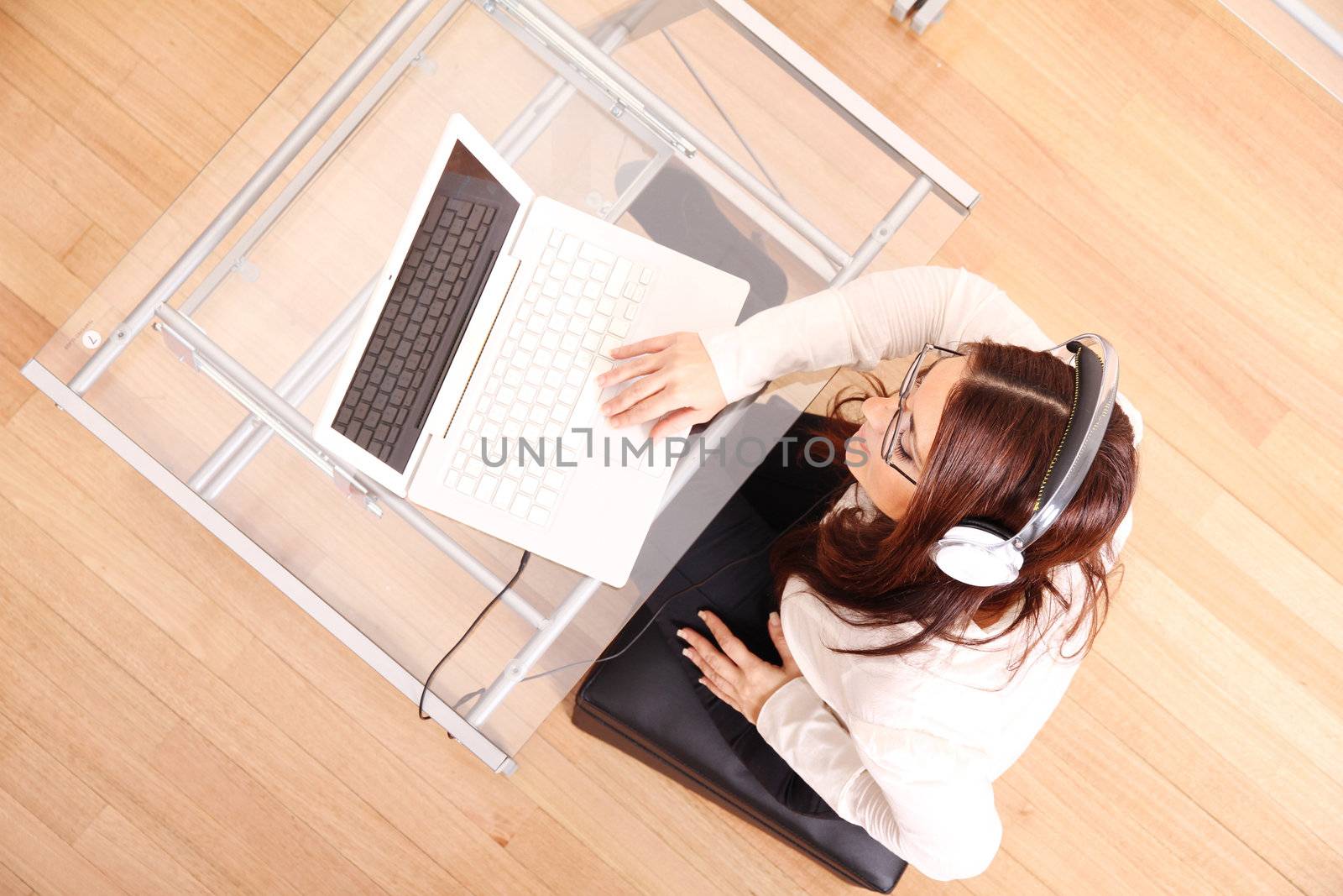 Business woman working on a Laptop while listening music with Headphones.