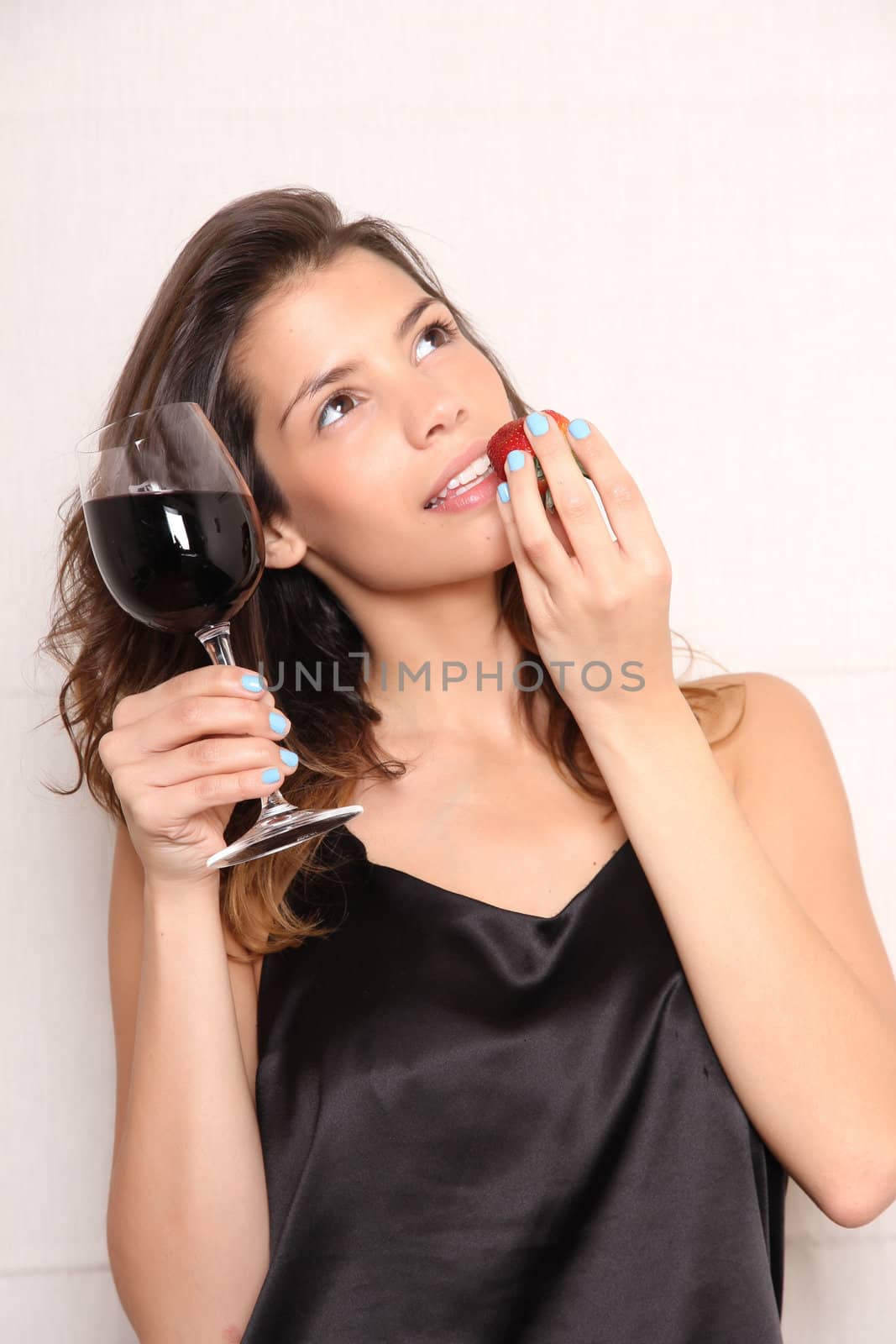 Portrait of a beautiful, latin Woman eating a Strawberry and drinking wine.