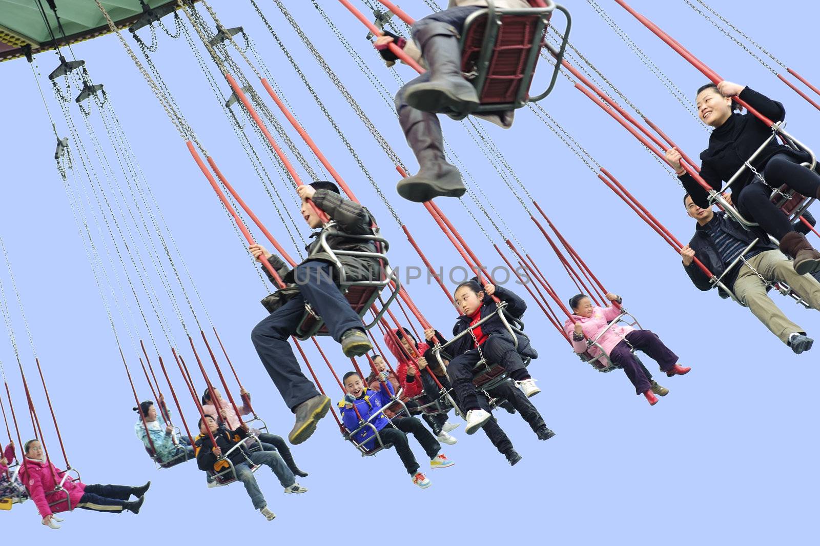 Happy people play chair chairoplane in the amusement park by jackq