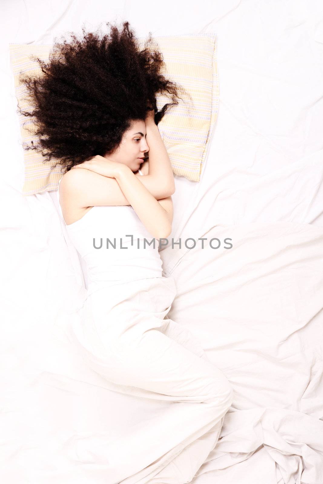 A young latin woman lying down in bed.