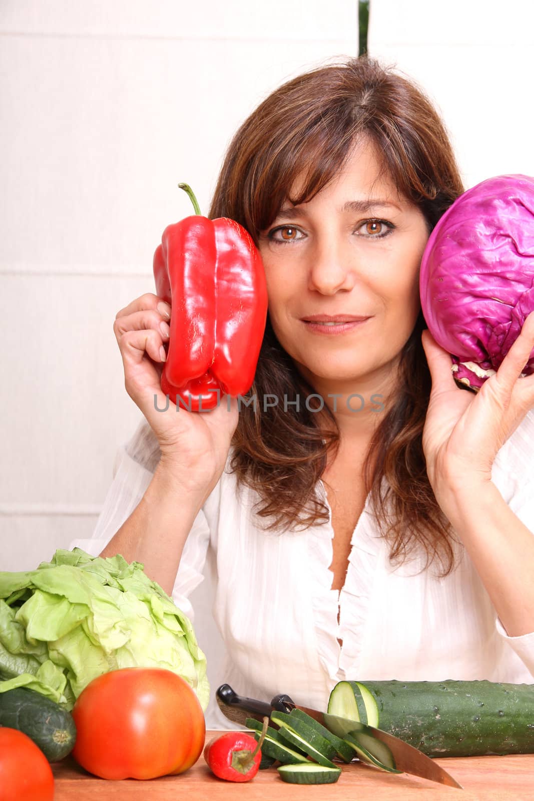 A mature woman holding vegetables.