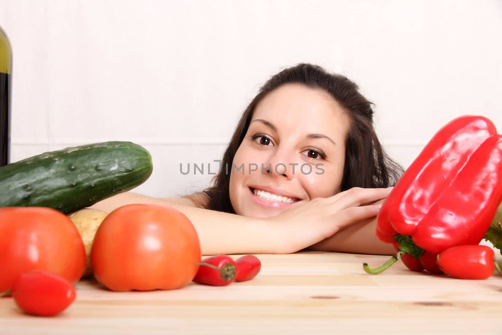 A young hispanic girl in the kitchen between vegetables.