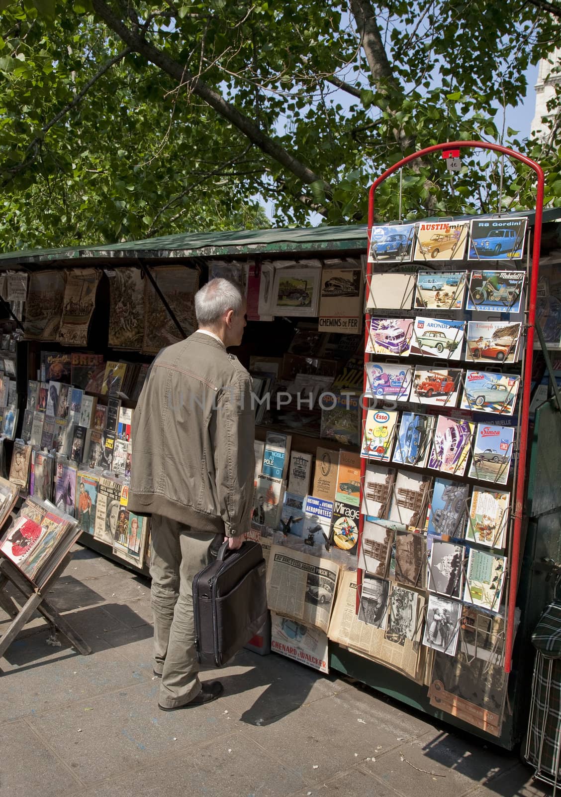 BOOK STAND LEFT SIDE, PARIS, FRANCE - APRIL 23, 2011: Male Parisian looking at a second hand book on the right side of the Seine at springtime.