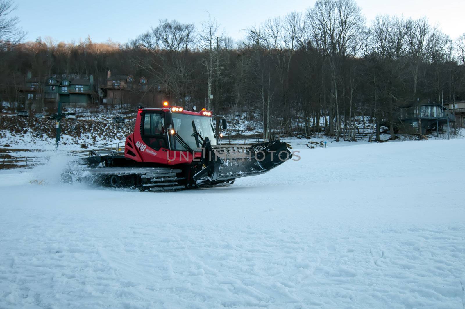 snow grooming machine at work smoothing out ski slope for skiing