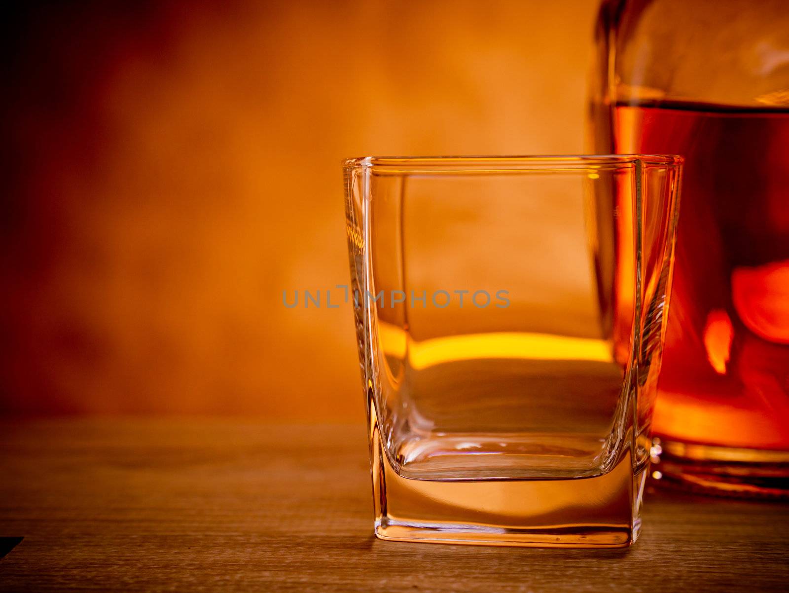 Bottle of whiskey with an empty glass waiting to be filled