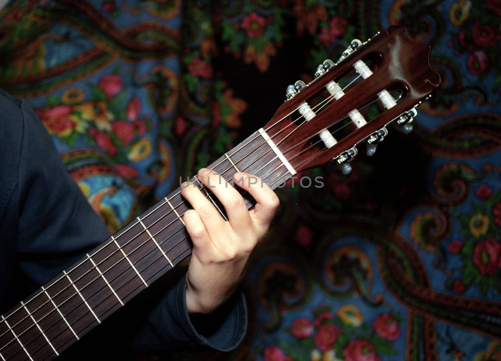 Hand on classic guitar fingerboard against Gipsy background