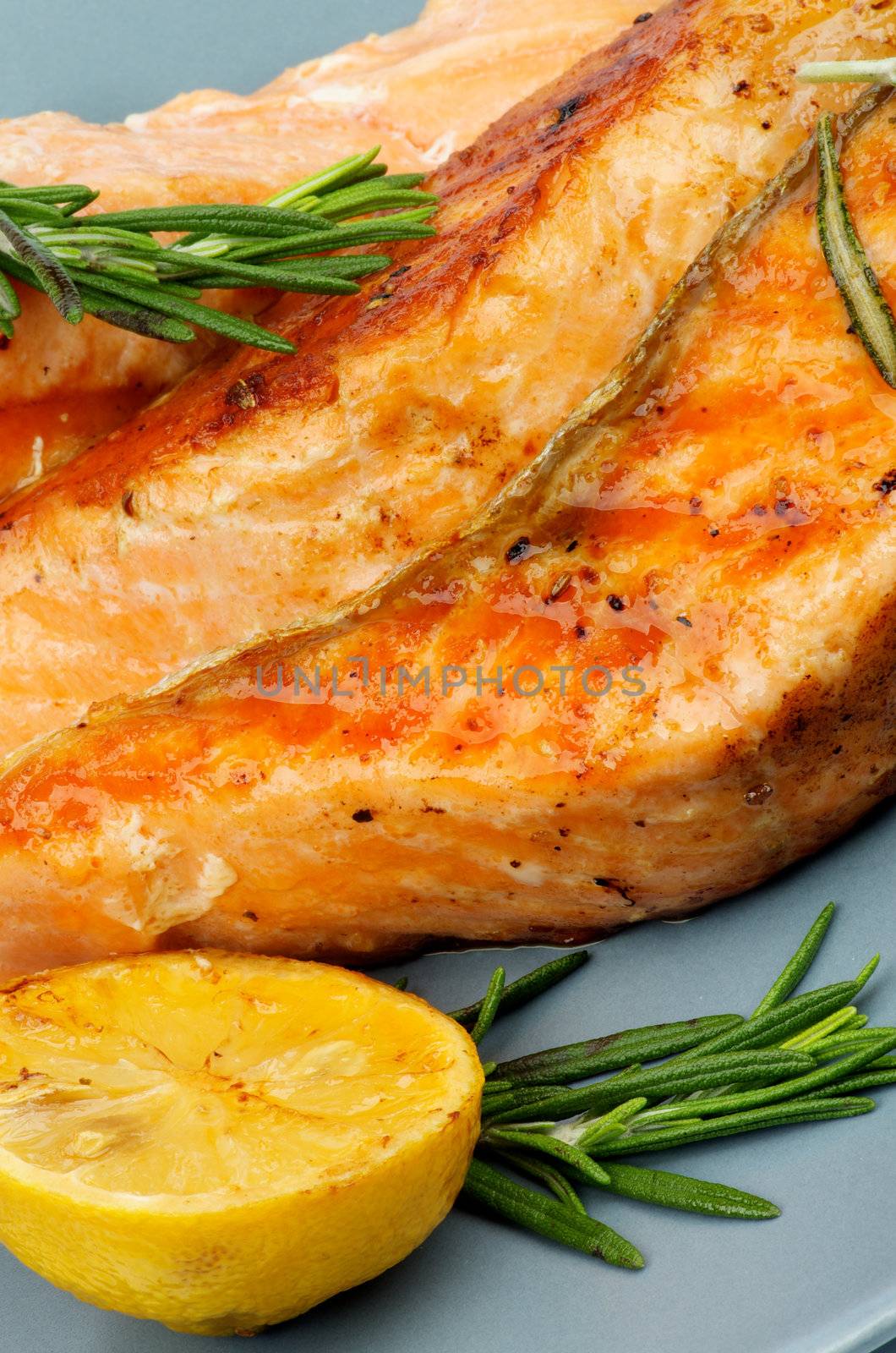 Delicious Grilled Salmon with Lemon and Rosemary closeup on Green Plate