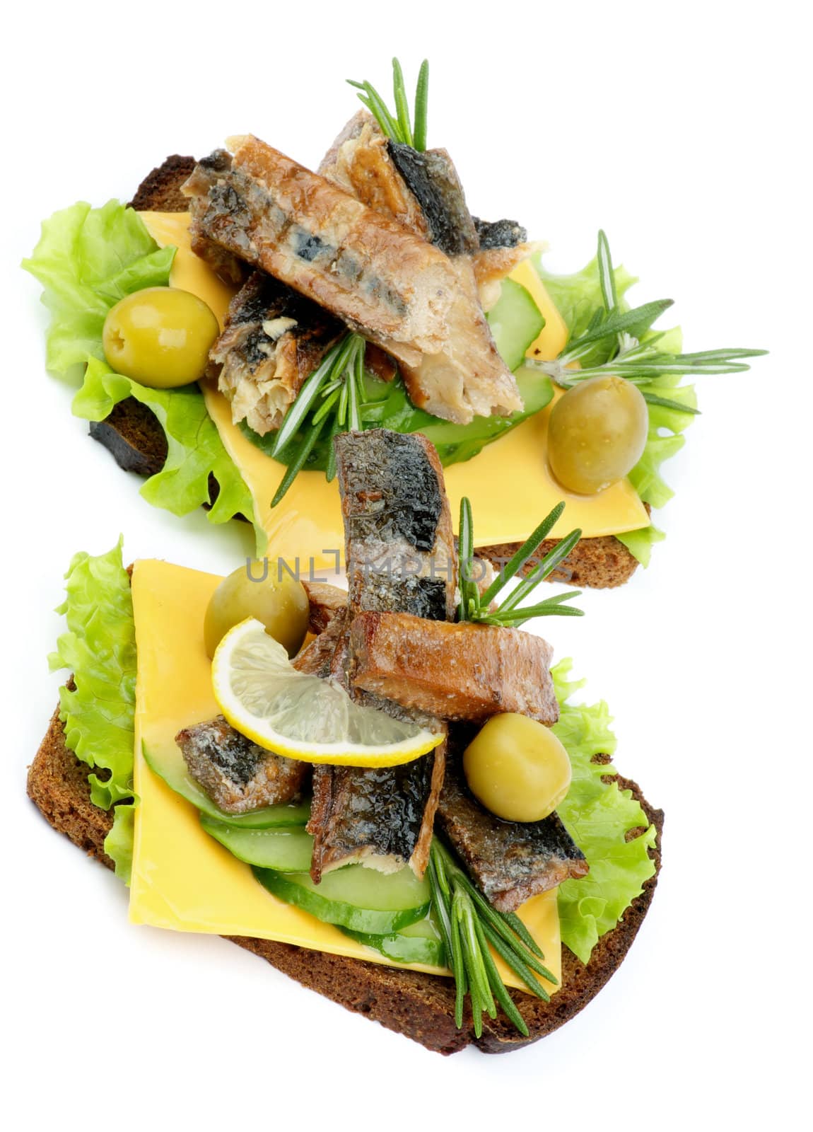 Two Sandwiches of Smoked Sardines with Cucumber, Cheese, Green Olive, Lettuce and Whole Wheat Bread closeup on white background