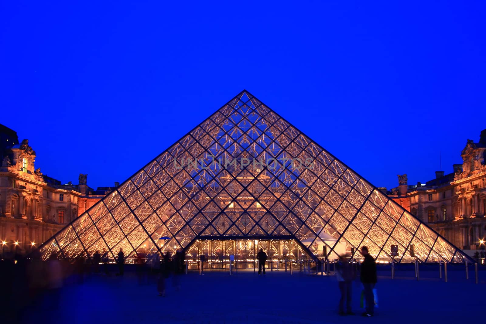 PARIS - APRIL 16: Entrance of Louvre pyramid shines at dusk during the Summer Exhibition April 16, 2010 in Paris. This is one of the most popular tourist destinations in France.