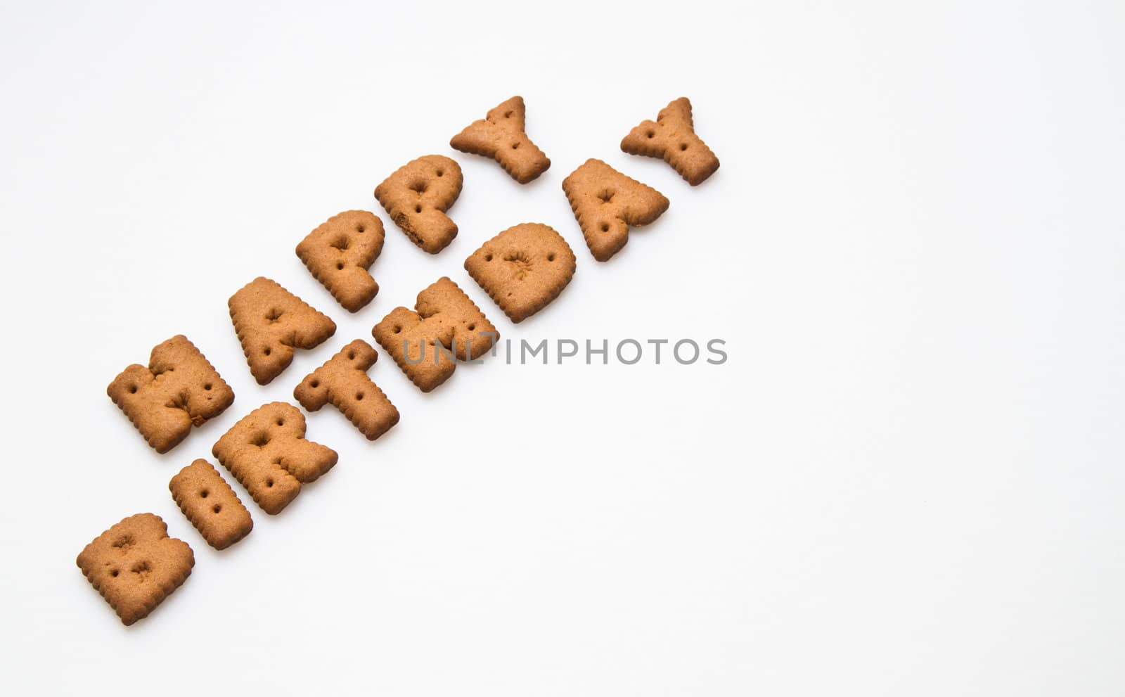 the words Happy Birthday made by brown biscuits slanting on white surface with copy space in landscape orientation