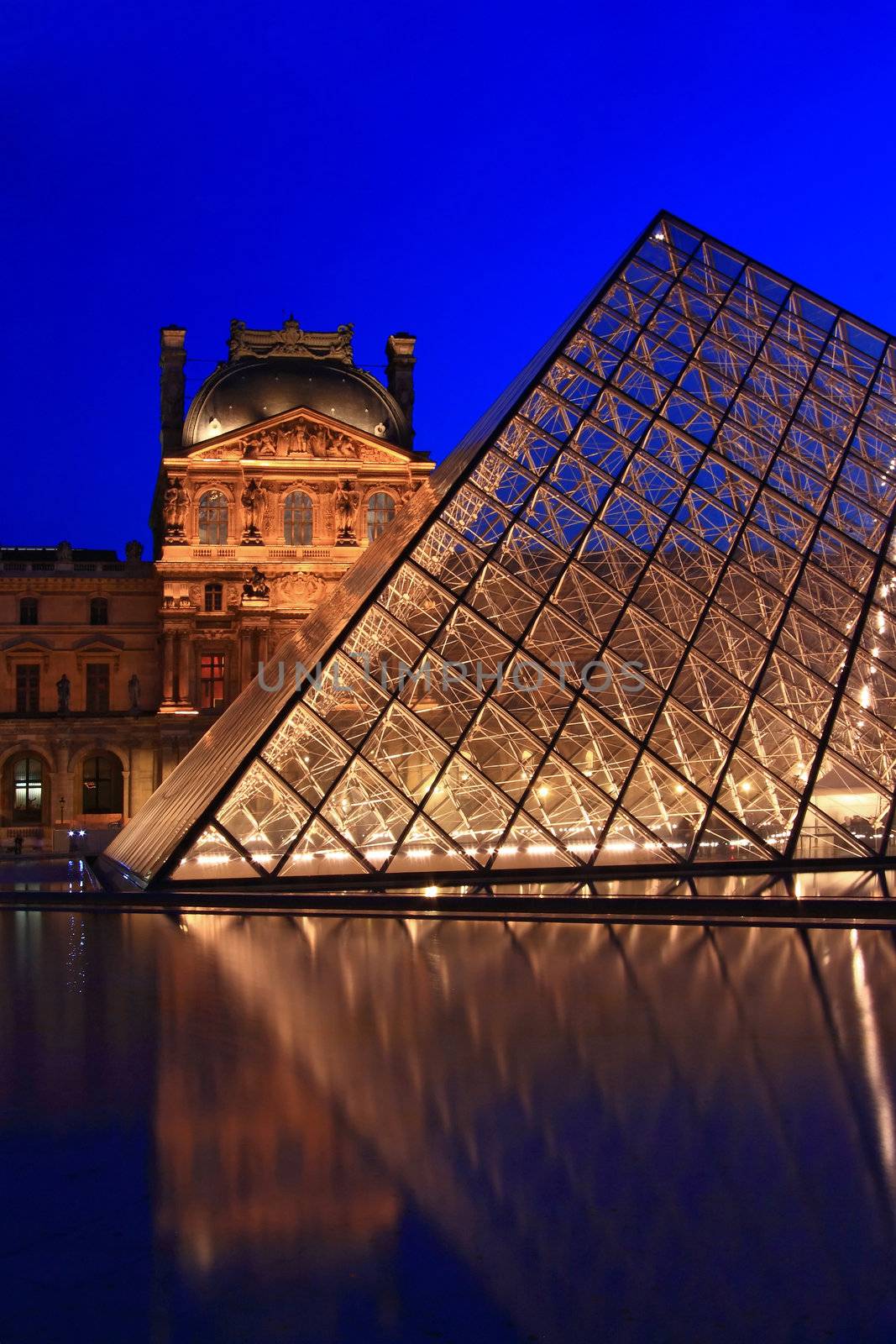 PARIS - APRIL 16: Closeup of Louvre pyramid shines at dusk during the Summer Exhibition April 16, 2010 in Paris. This is one of the most popular tourist destinations in France.