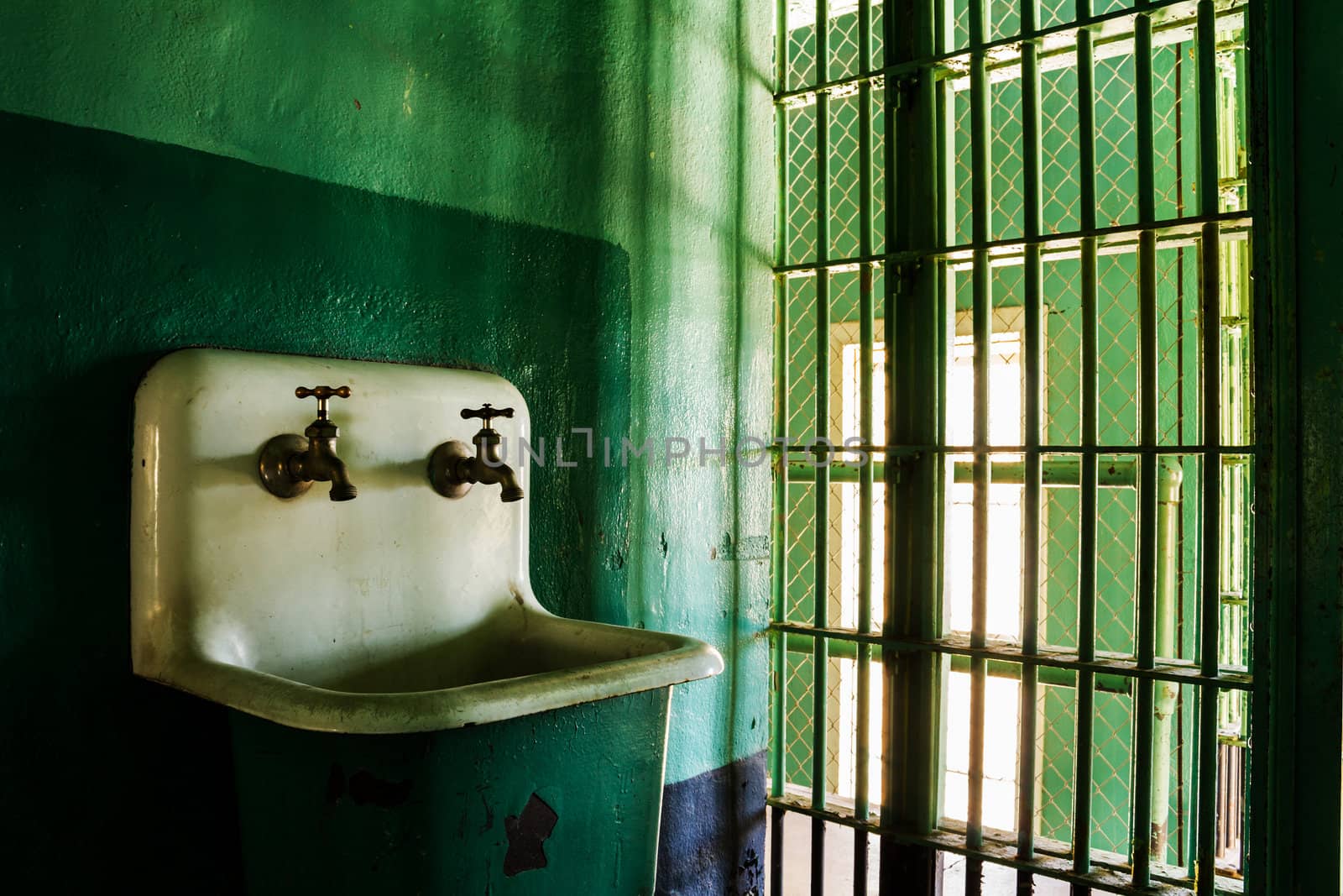 Behind the bars of a local prison ther is a dirty sink that could use some cleaning