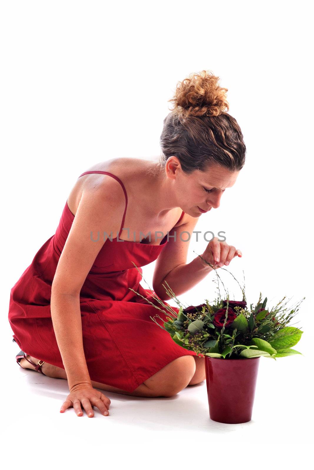 beautiful woman arranging flowers in front of a white background