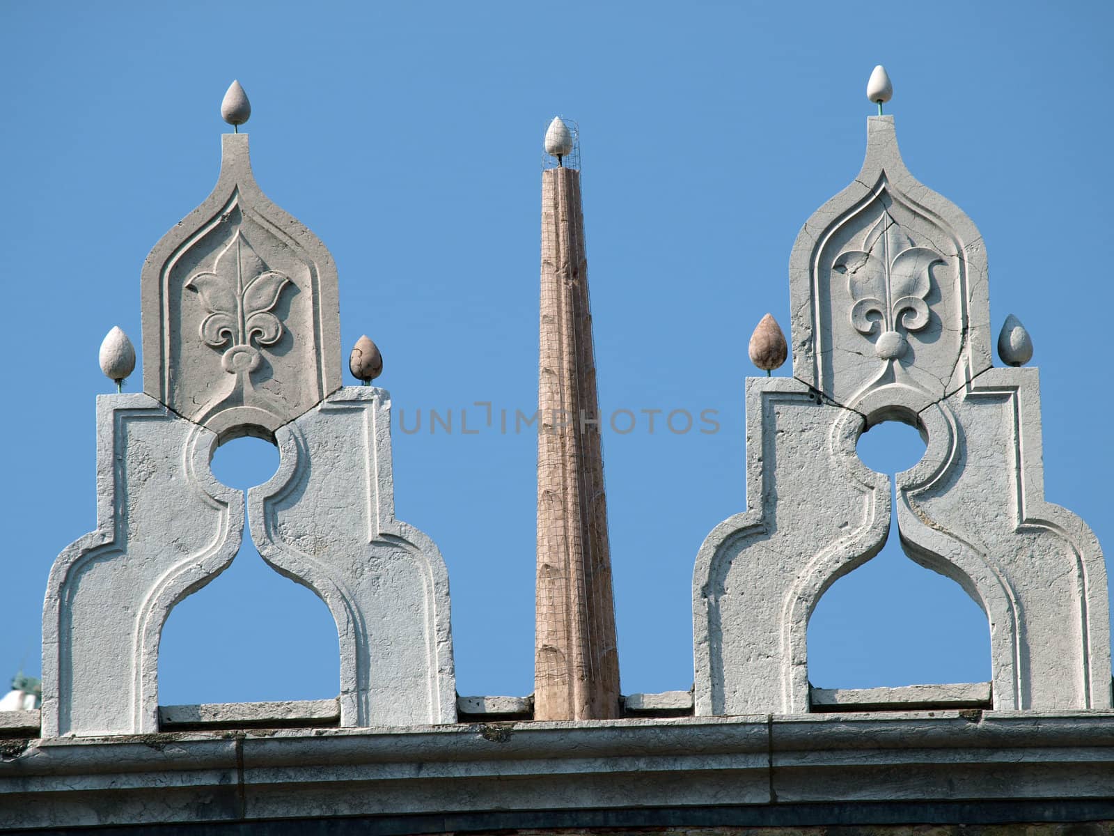 Venice - characteristic architectural ornaments on the edge of a roof of the Palace of Doges.  These are they at the top and the colonnade at the bottom are granting this unique rhythm this building