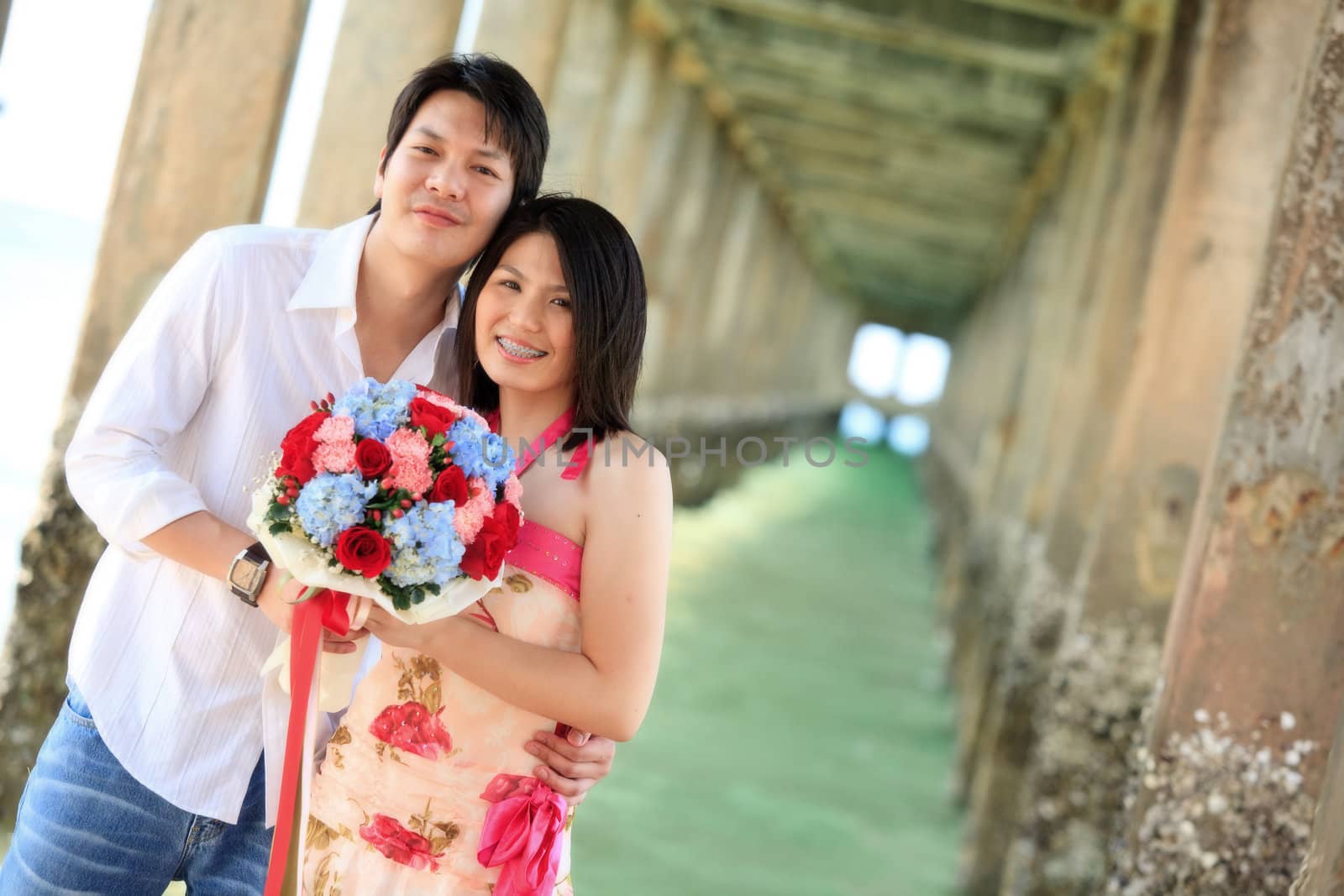 portrait of attractive couples under the pier on the beach by vichie81