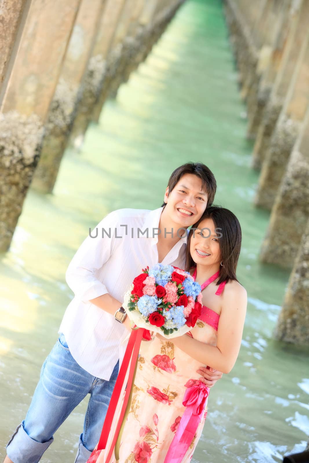 portrait of smiling couples under the pier on the beach
