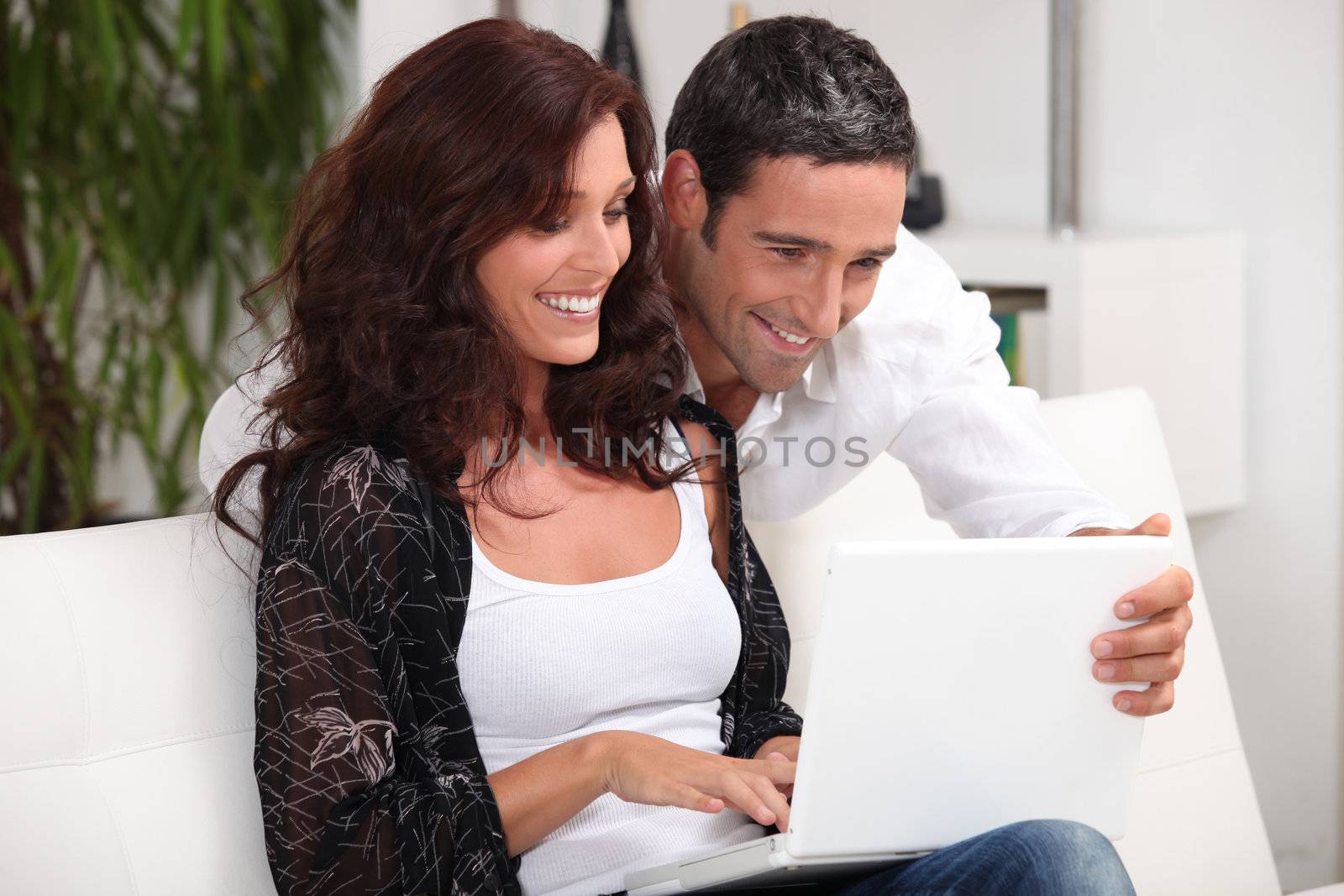 Couple looking at photos on their laptop and reminiscing by phovoir