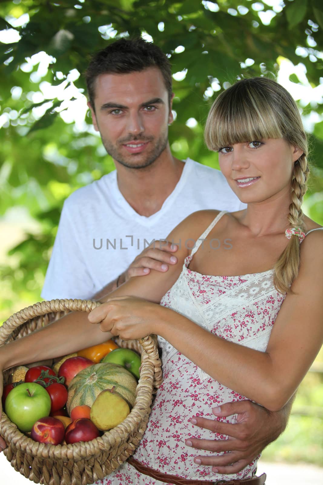 Young couple in park with fruit basket by phovoir