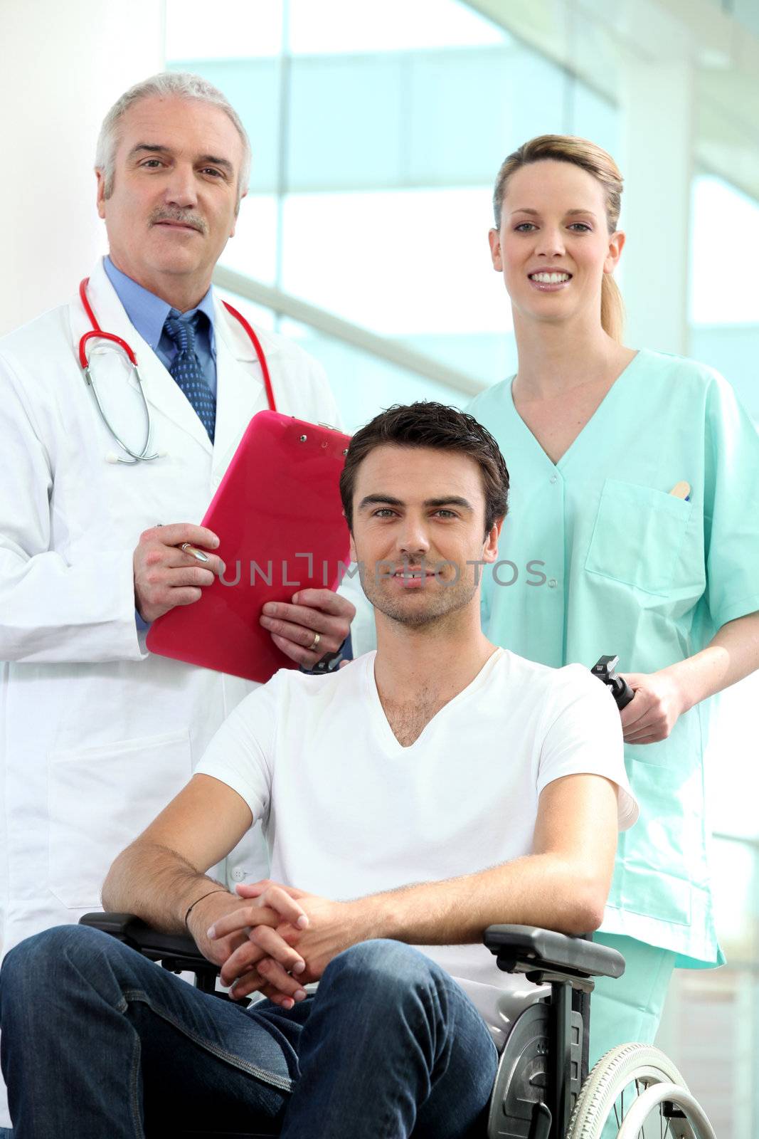 Doctor and nurse with patient in wheelchair by phovoir