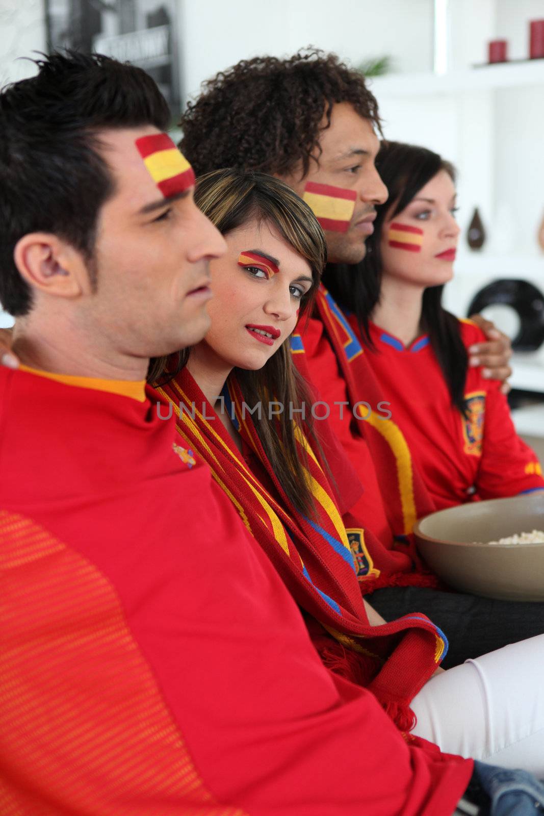 portrait of Spanish supporters watching soccer match on telly by phovoir