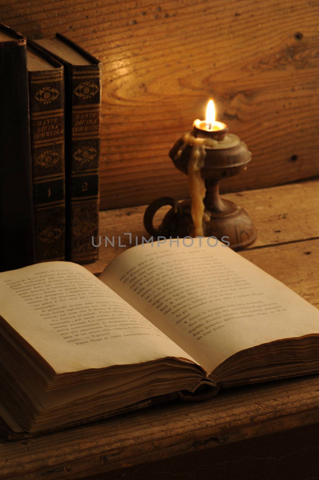 old book on a wooden table by candlelight by stokkete