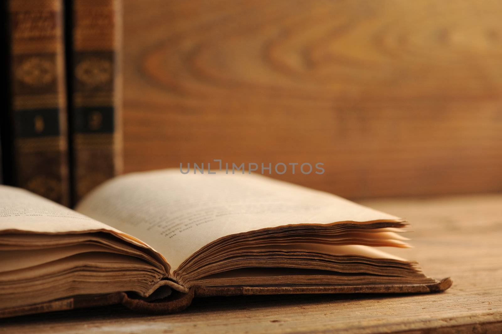 old book open on a wooden table by stokkete