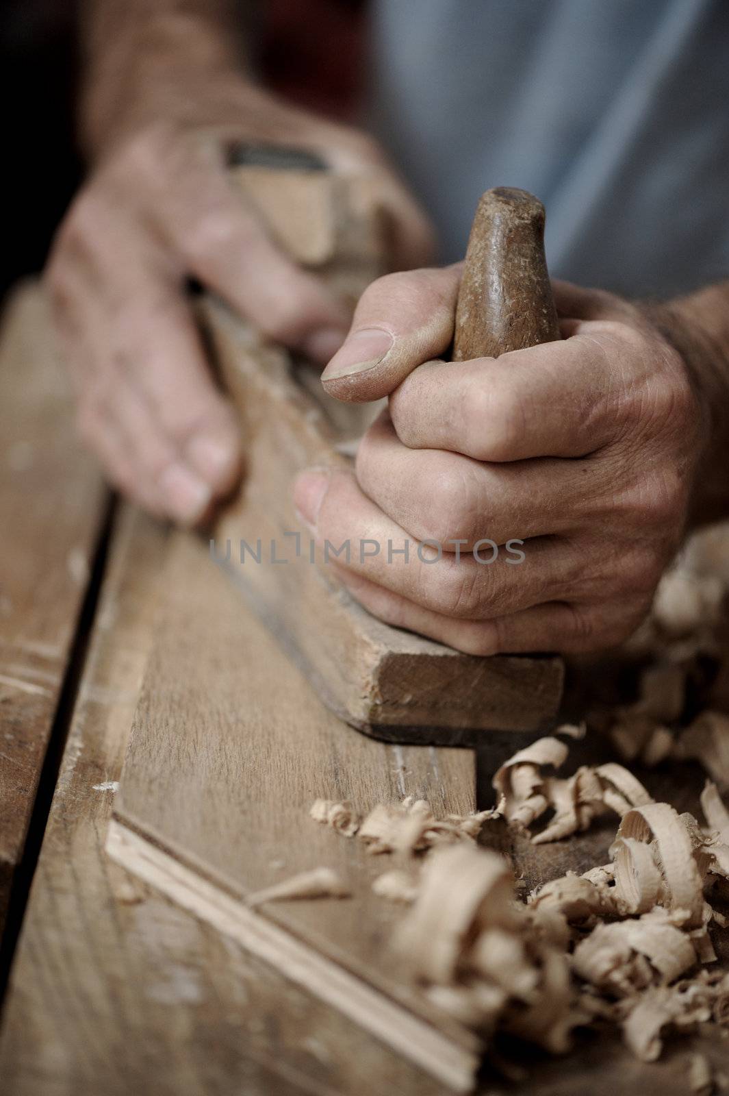 Man hands with carpenter's plane on wooden background  by stokkete