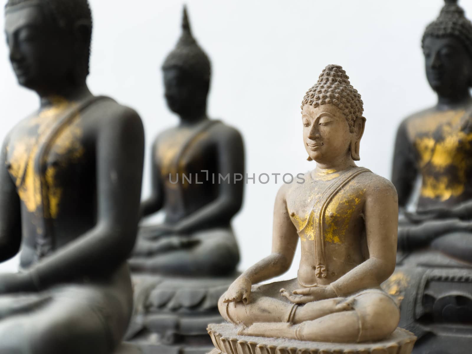 One Old Light Stone Buddha in focus and Three Dark out of focus