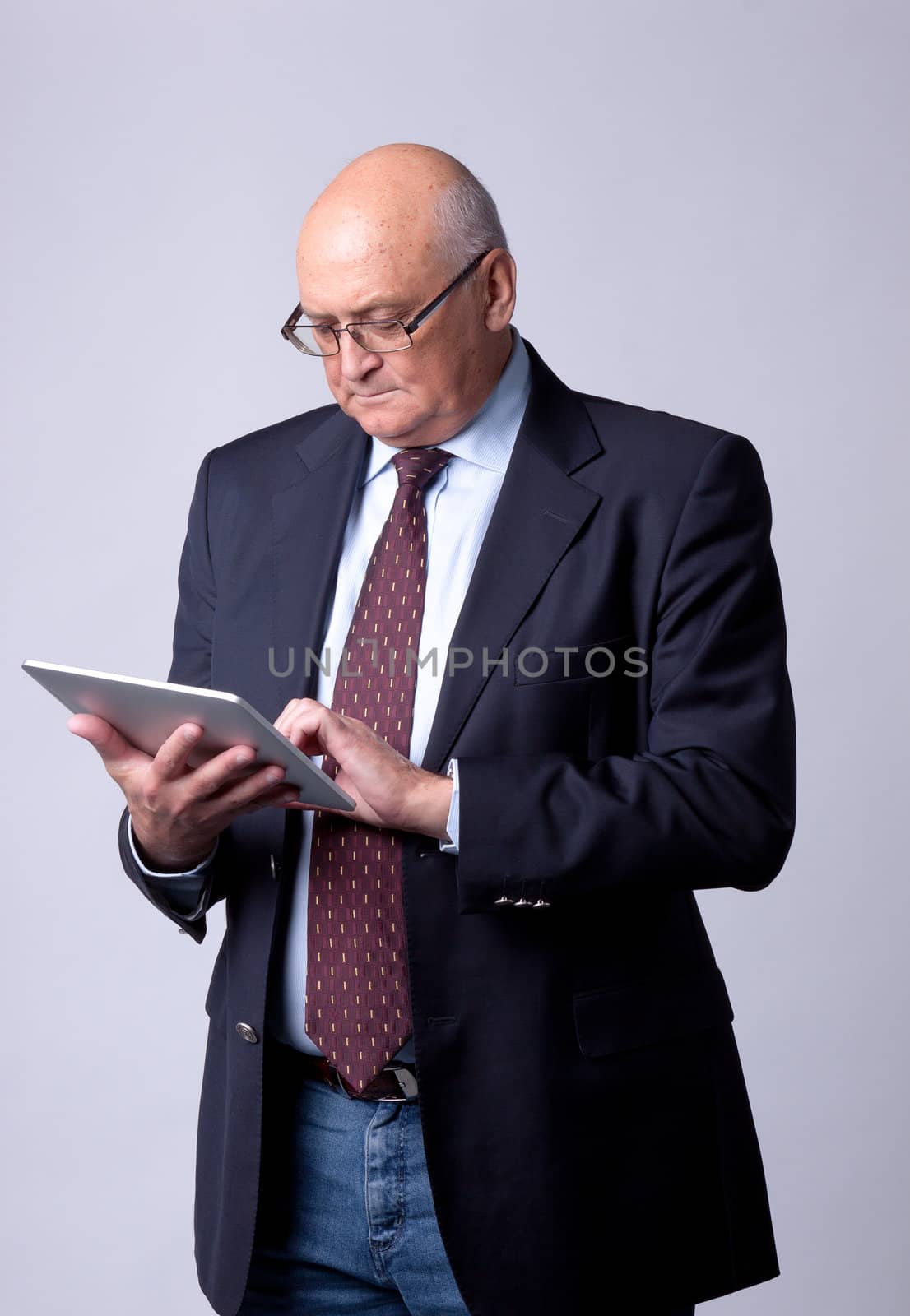 portrait of a successful senior man with tablet on gray background