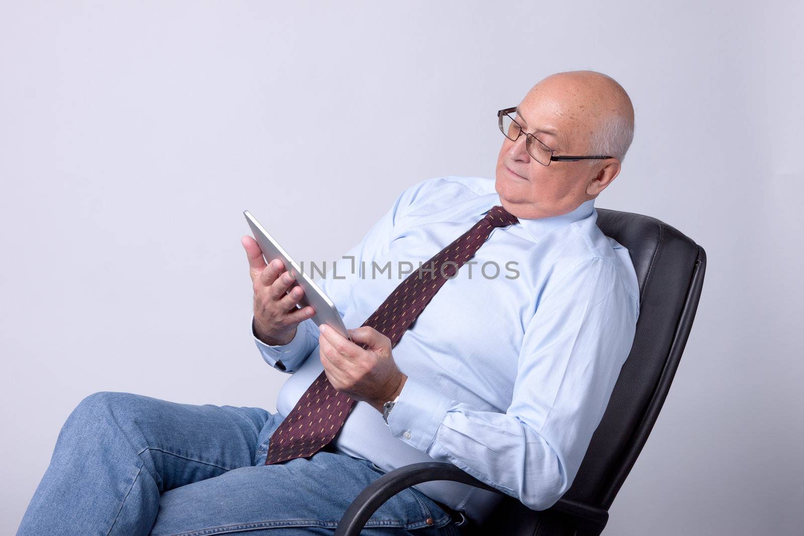 portrait of a successful senior man with tablet on gray background