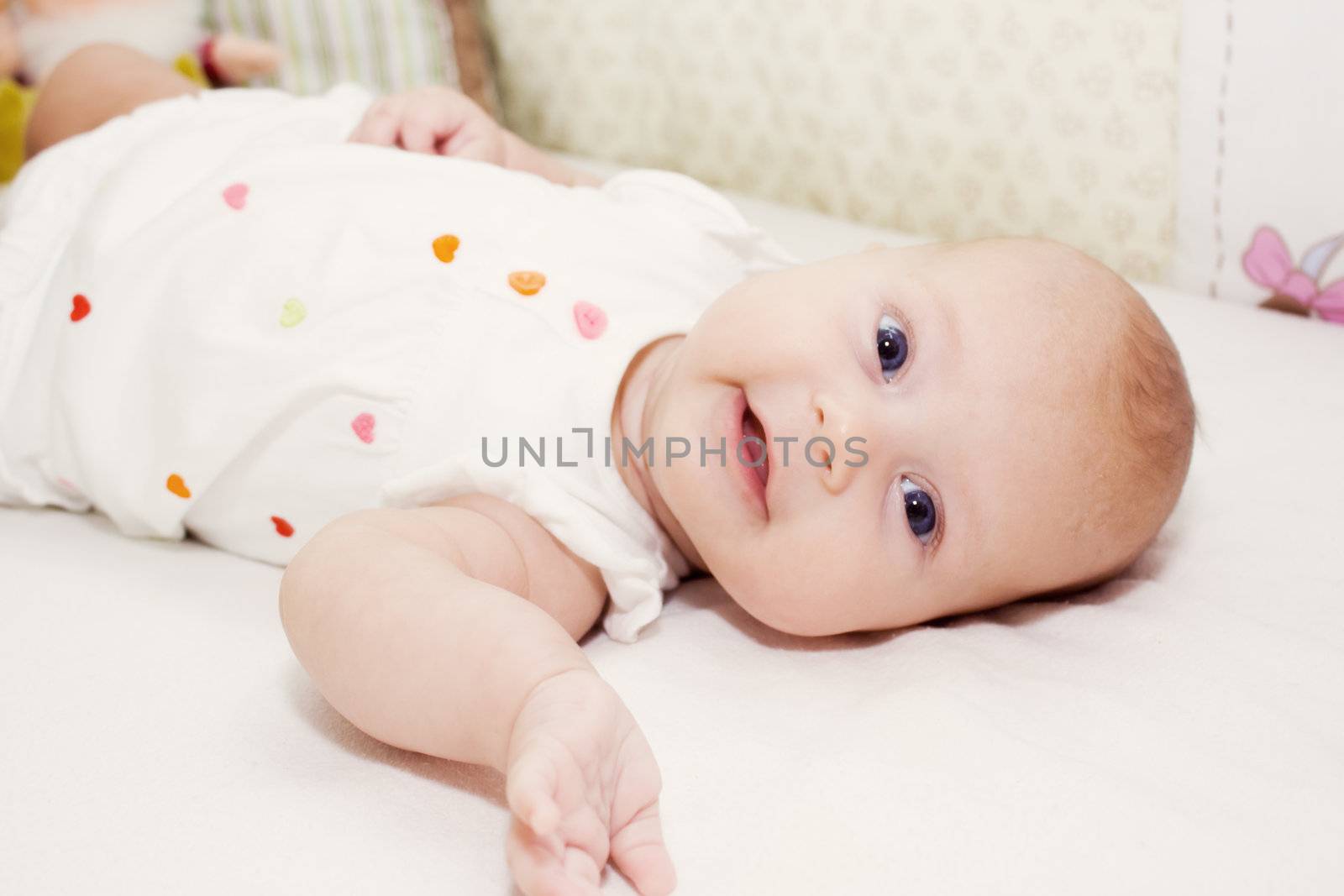 the portrait of little girl in her bed smiling and showing her hand