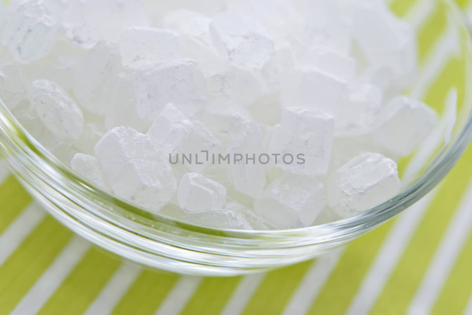 White rock candy  or sugar cubes on white and green striped background