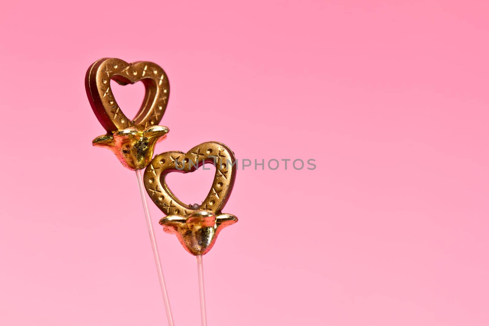 two brown plastic hearts on pink background in landscape orientation for valentine