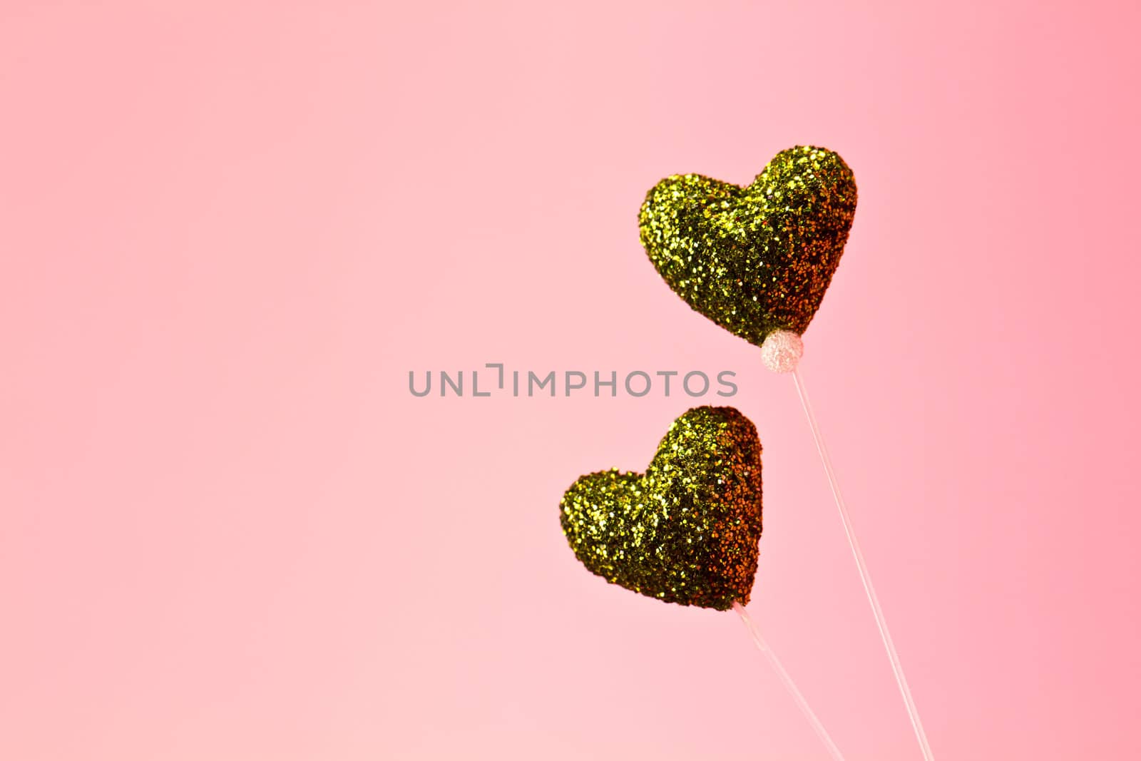 two glittering green heart made by styrofoam on pink background