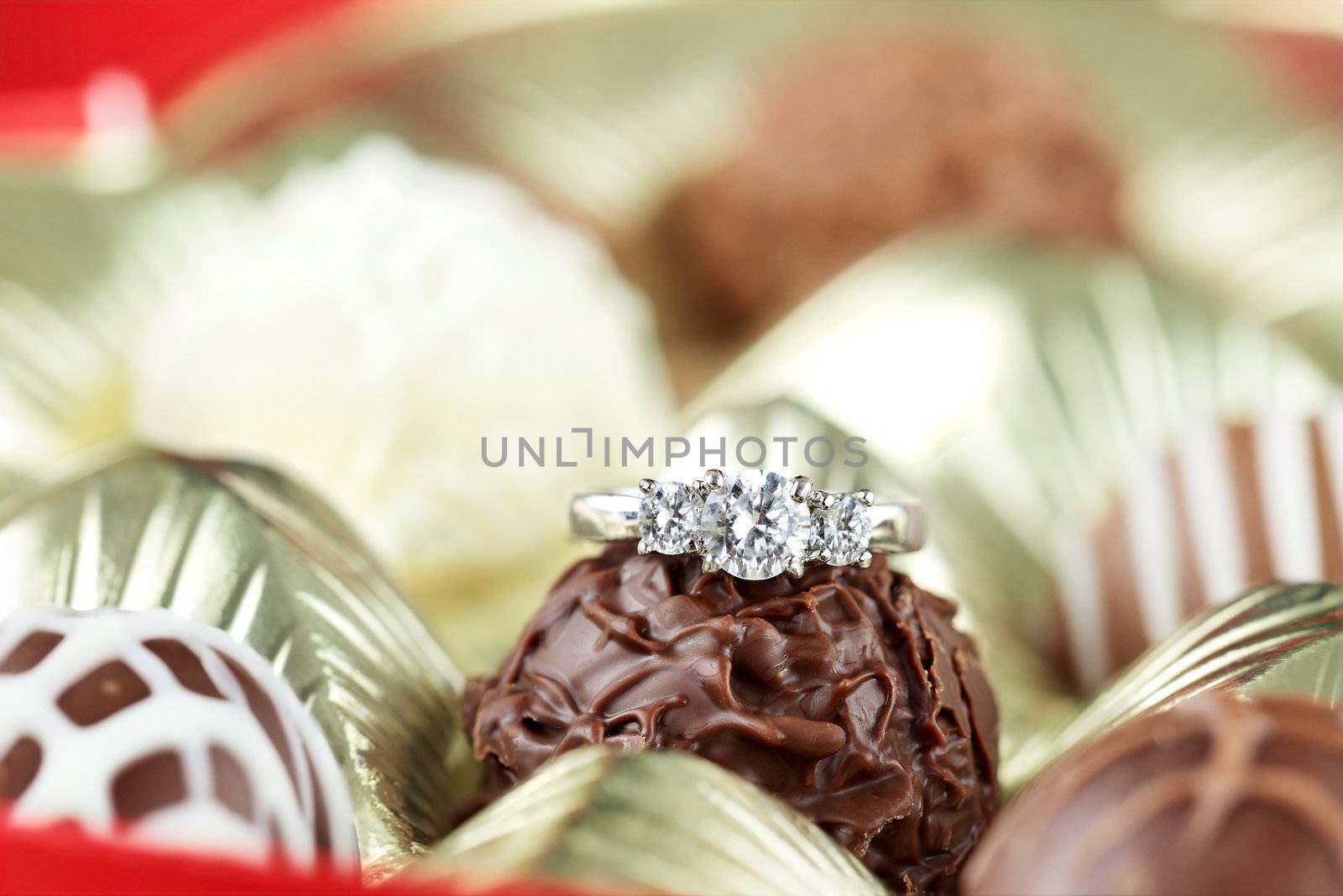 Diamond engagement inside of a box of chocolate truffles. Extreme shallow depth of field with selective focus on diamond ring. 