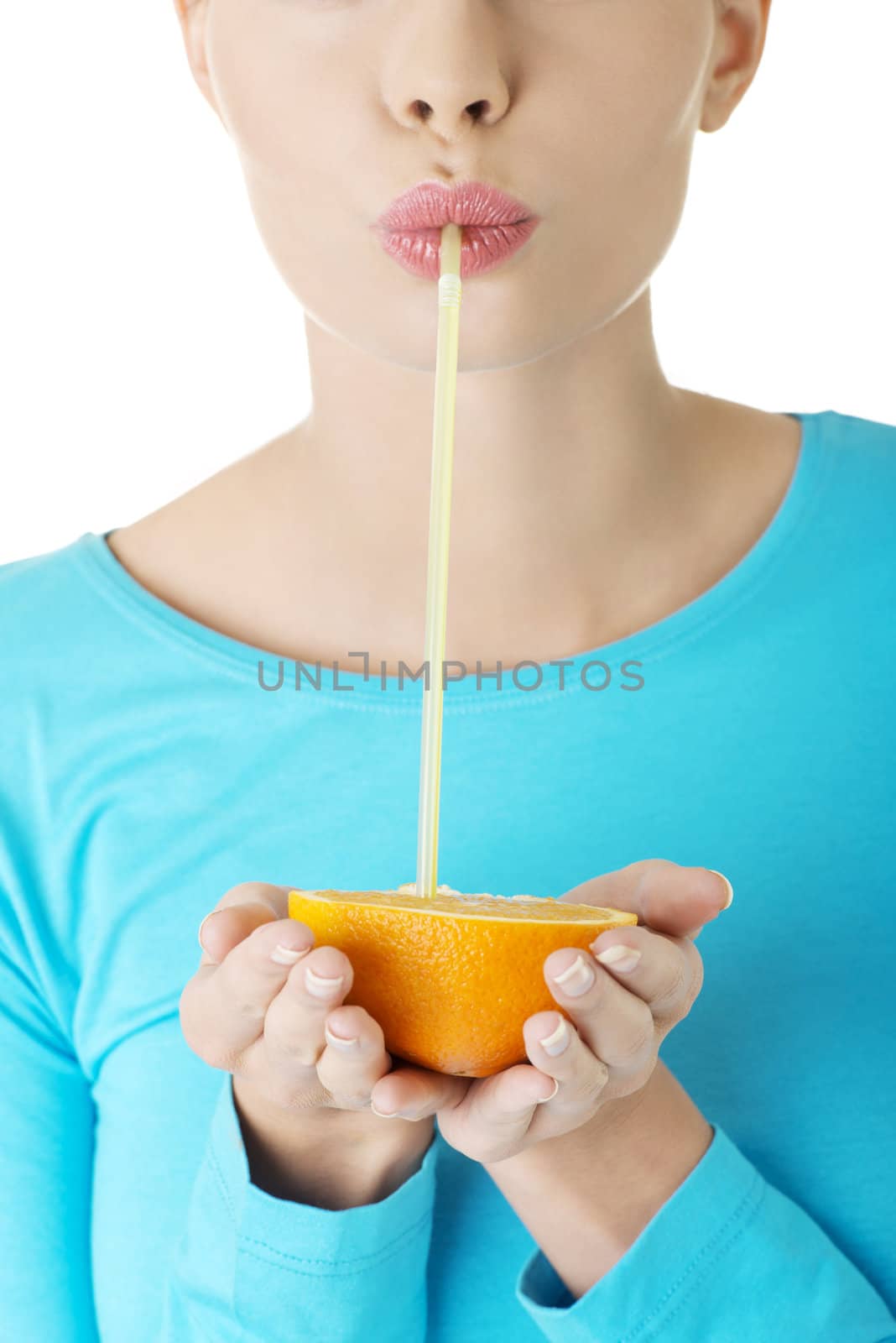 Attractive smiling young woman drinking orange juice straight from fruit