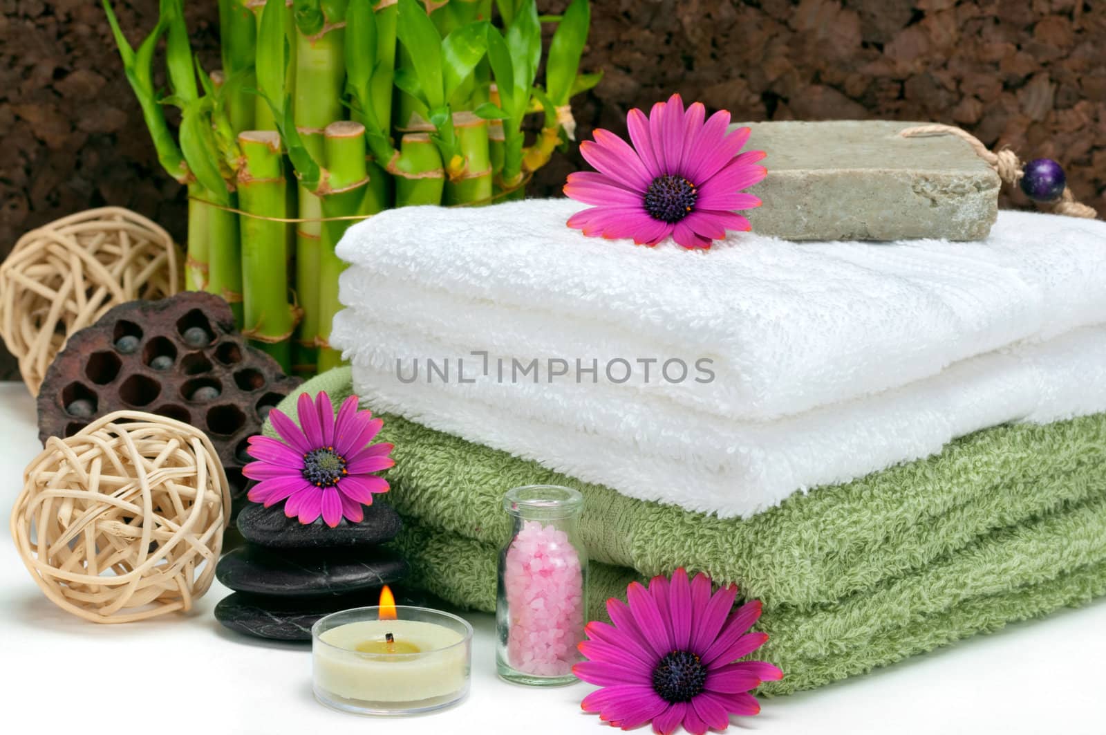 Spa scene with bamboo, towels, aromatic candles, bath salt, pebbles and daisies