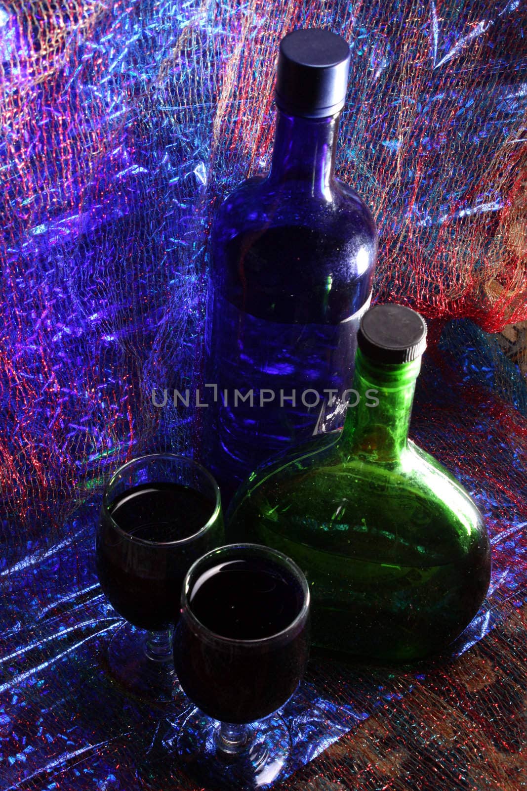 Bottles of liquor and glasses in colorful party lights.