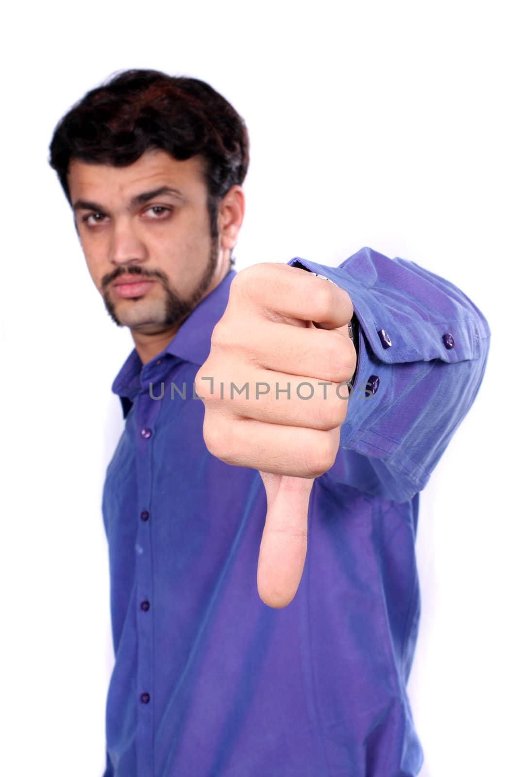 An Indian man showing the thumbs down sign meaning denial or bad luck, on white studio background. Focus on hand.