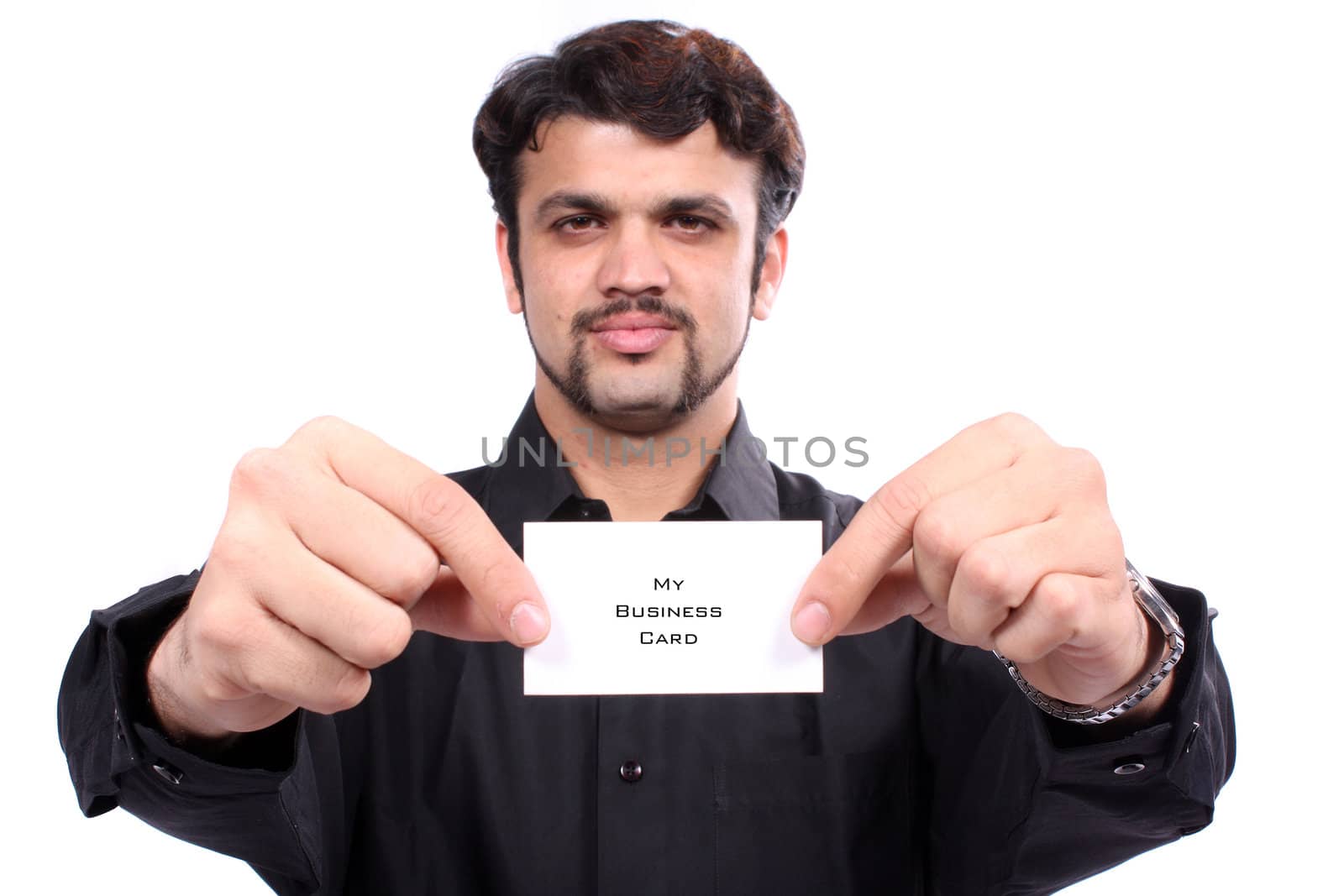 A proud Indian man showing his new business card, on white studio background. Focus on hands and the card.