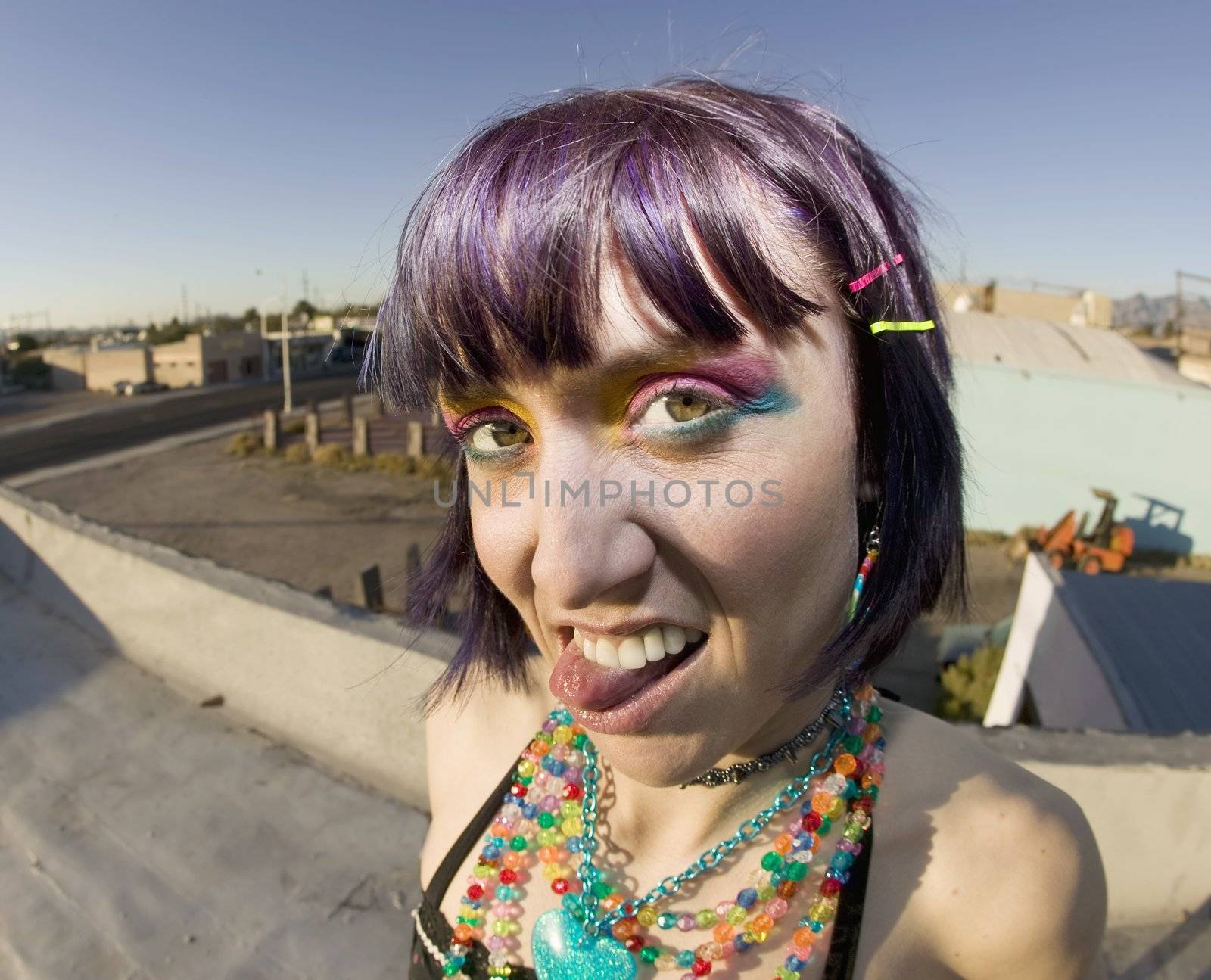 Cute young woman on a roof sticking out her tongue by Creatista