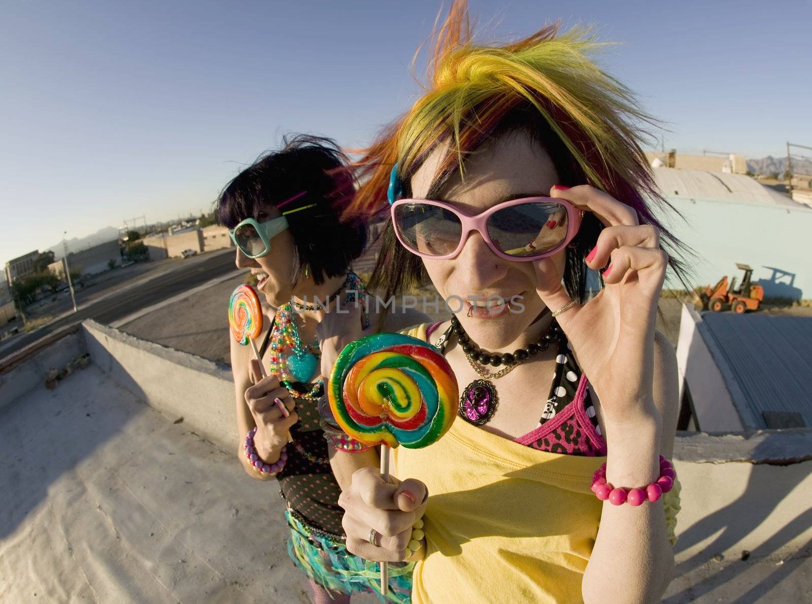 Fisheye shot of girls in brightly colored clothing on a roof with sunglasses and lollipops
