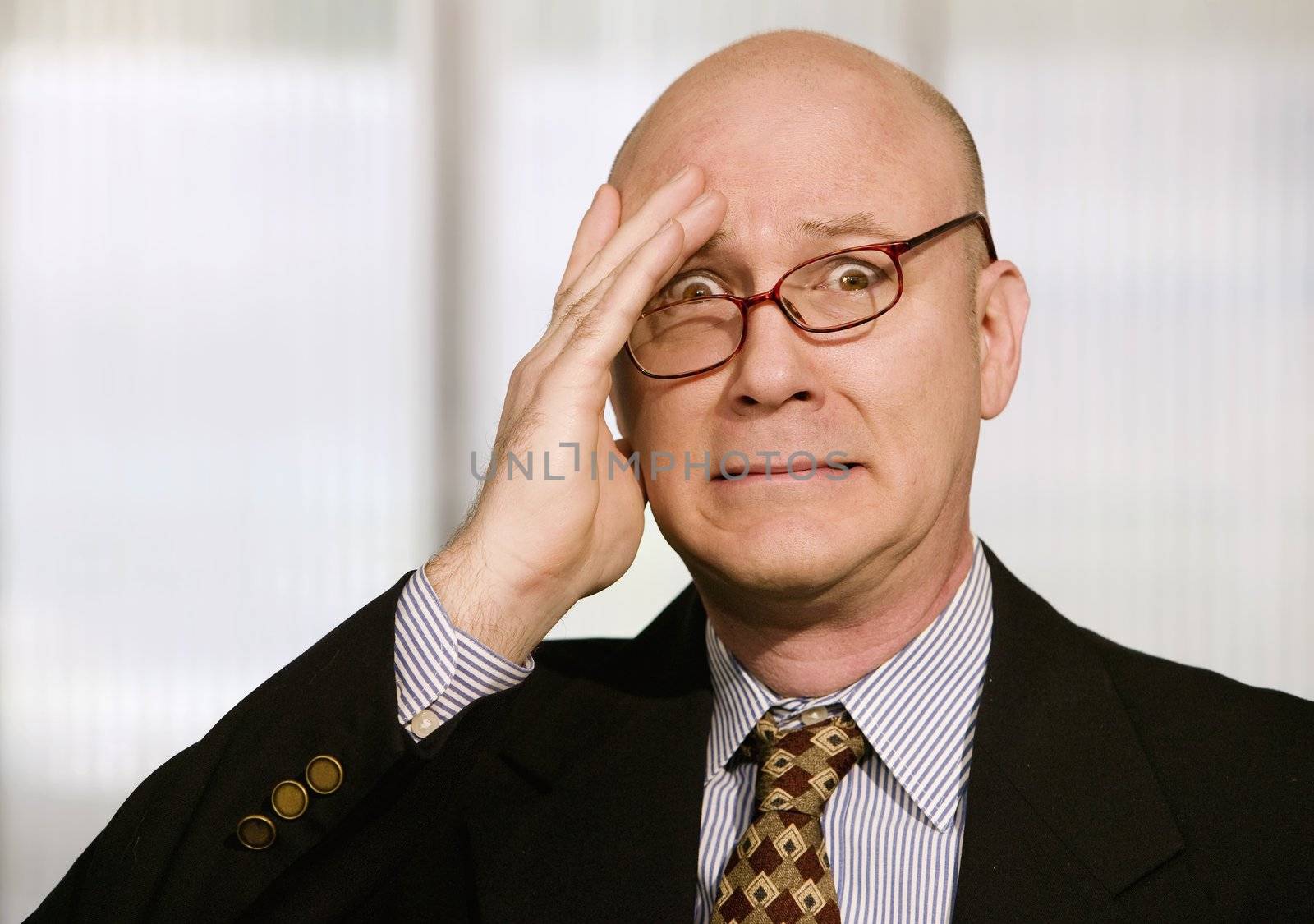 Frustrated businessman with his glasses askew and a hand to his forehead