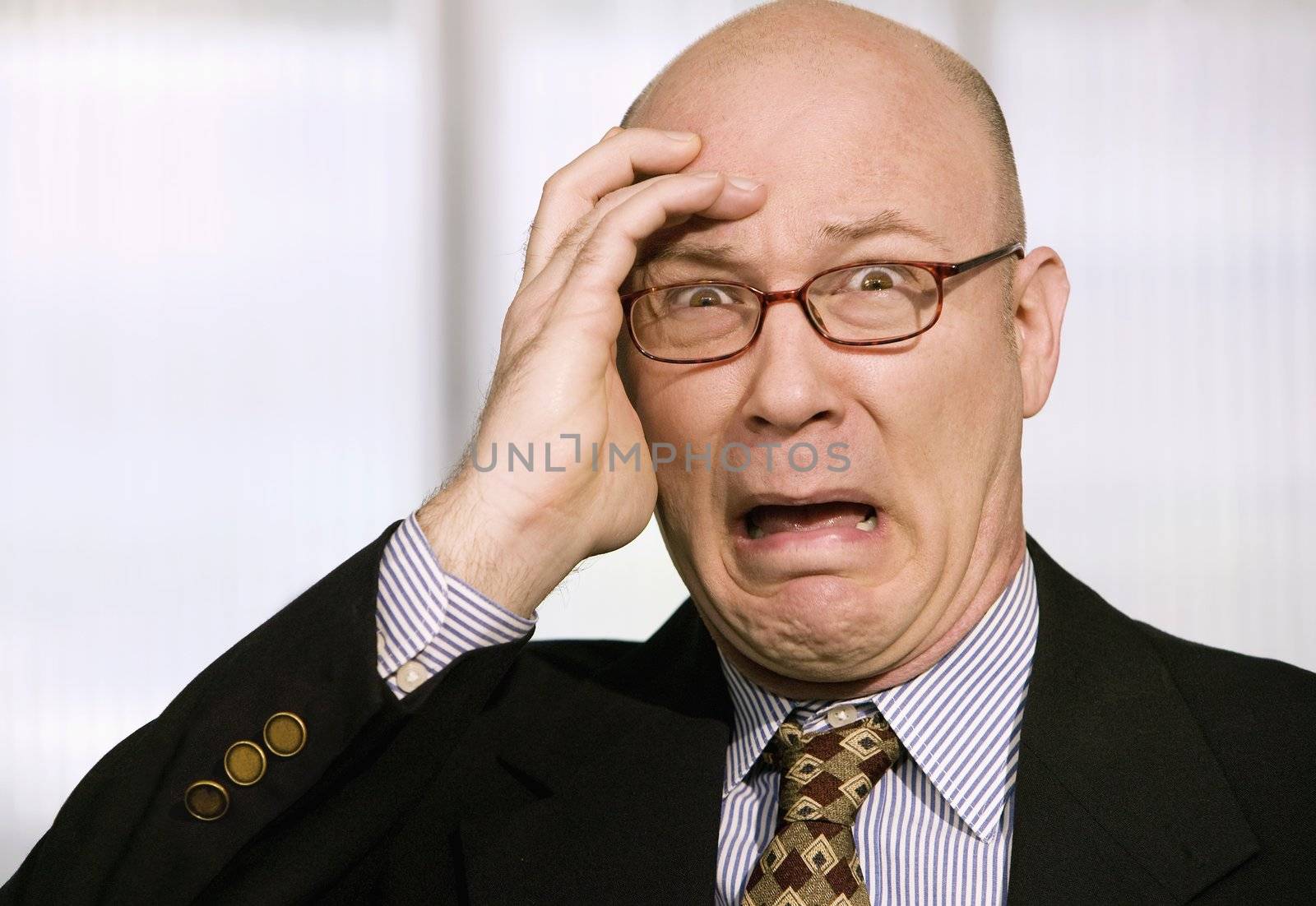 Horrified businessman with a hand to his forehead