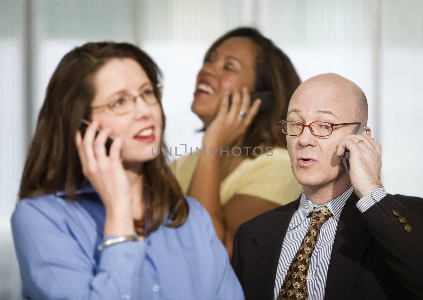 Selective focus on three businesspeople using cell phones