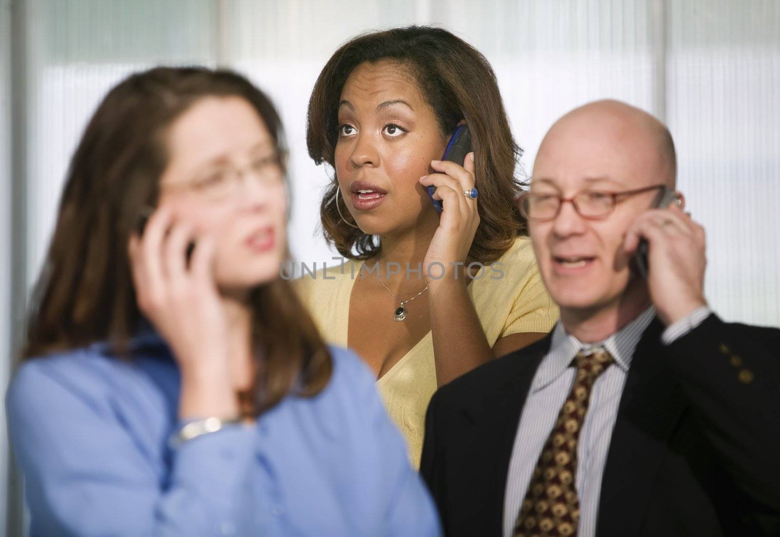 Selective focus on three businesspeople using cell phones
