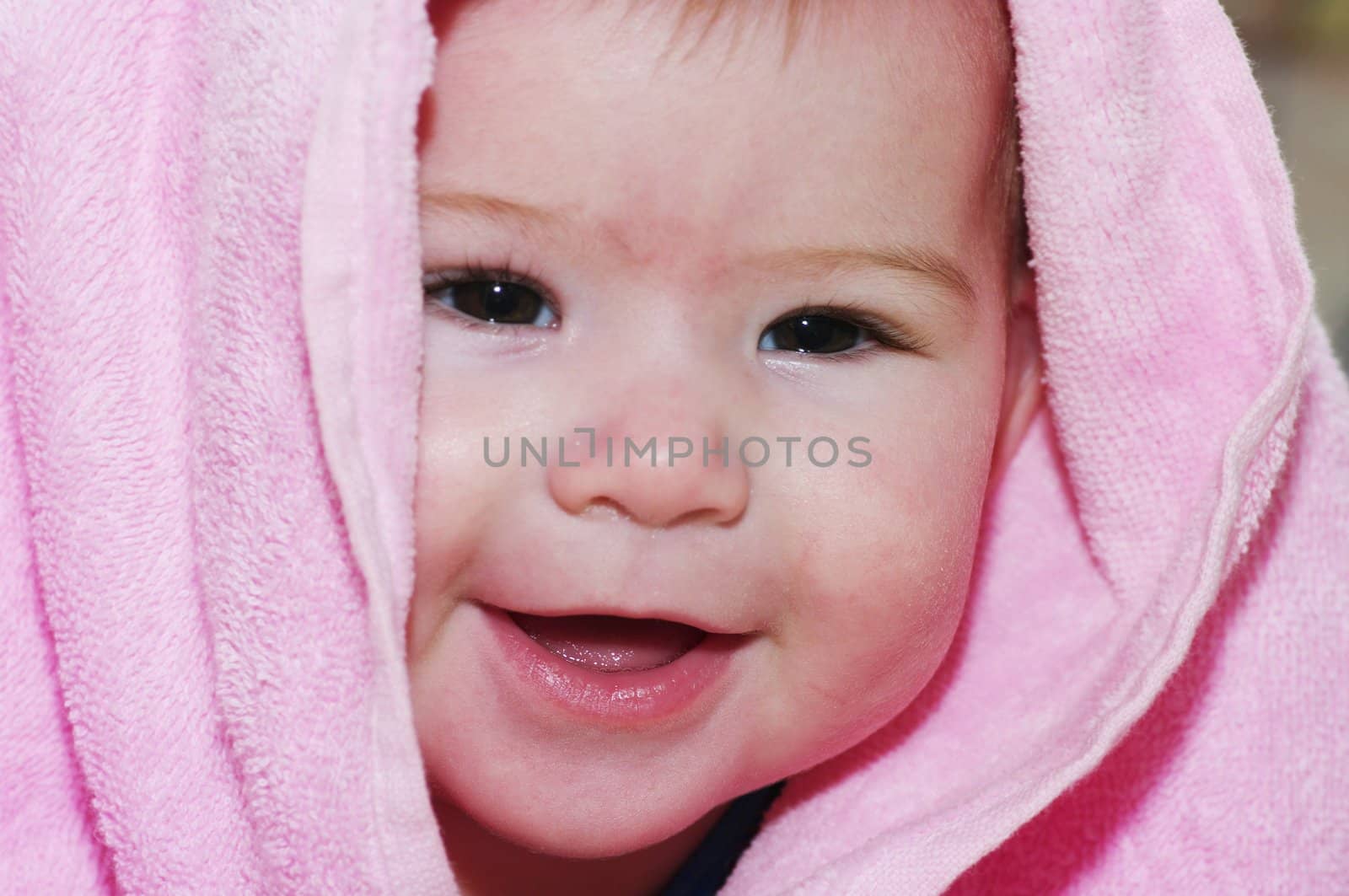 baby looking out and smiling from under blanket