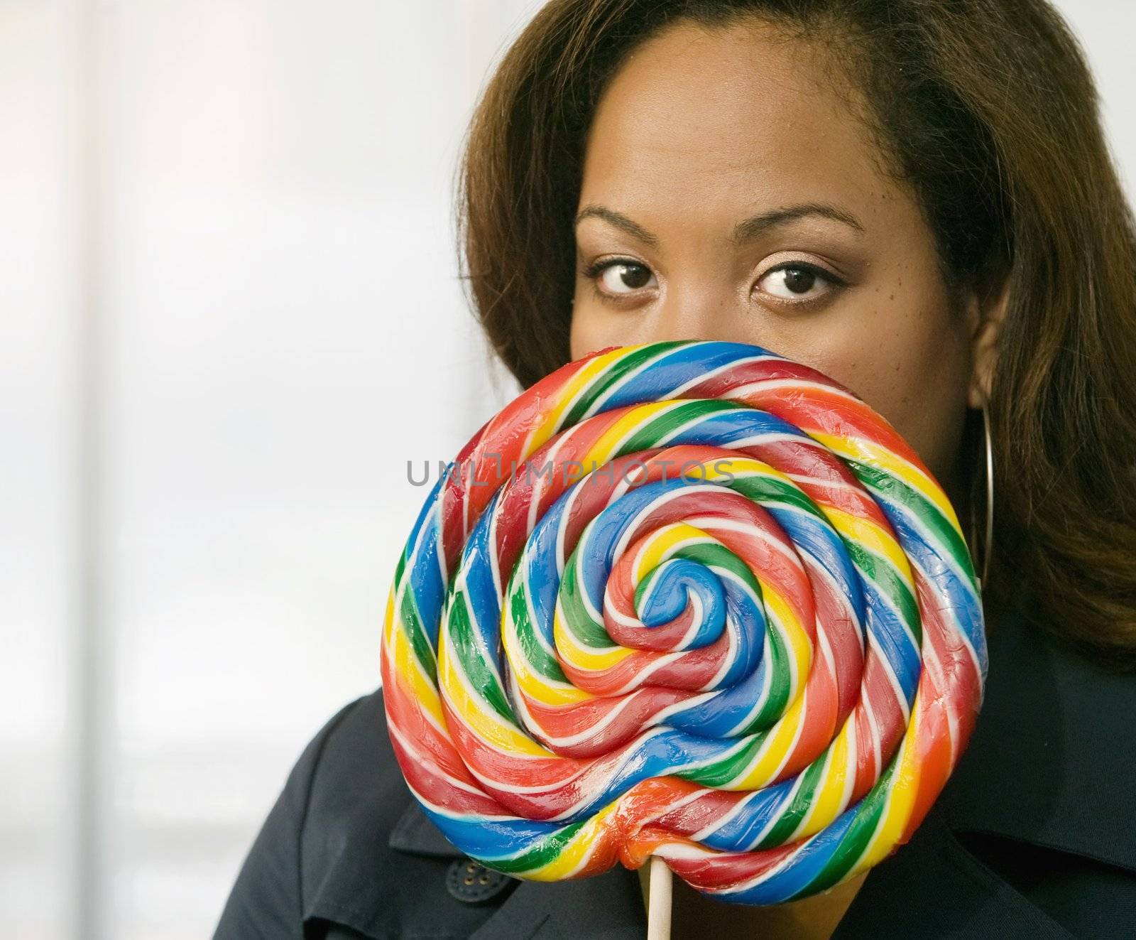 African-American woman stares from behind a colorful lollipop