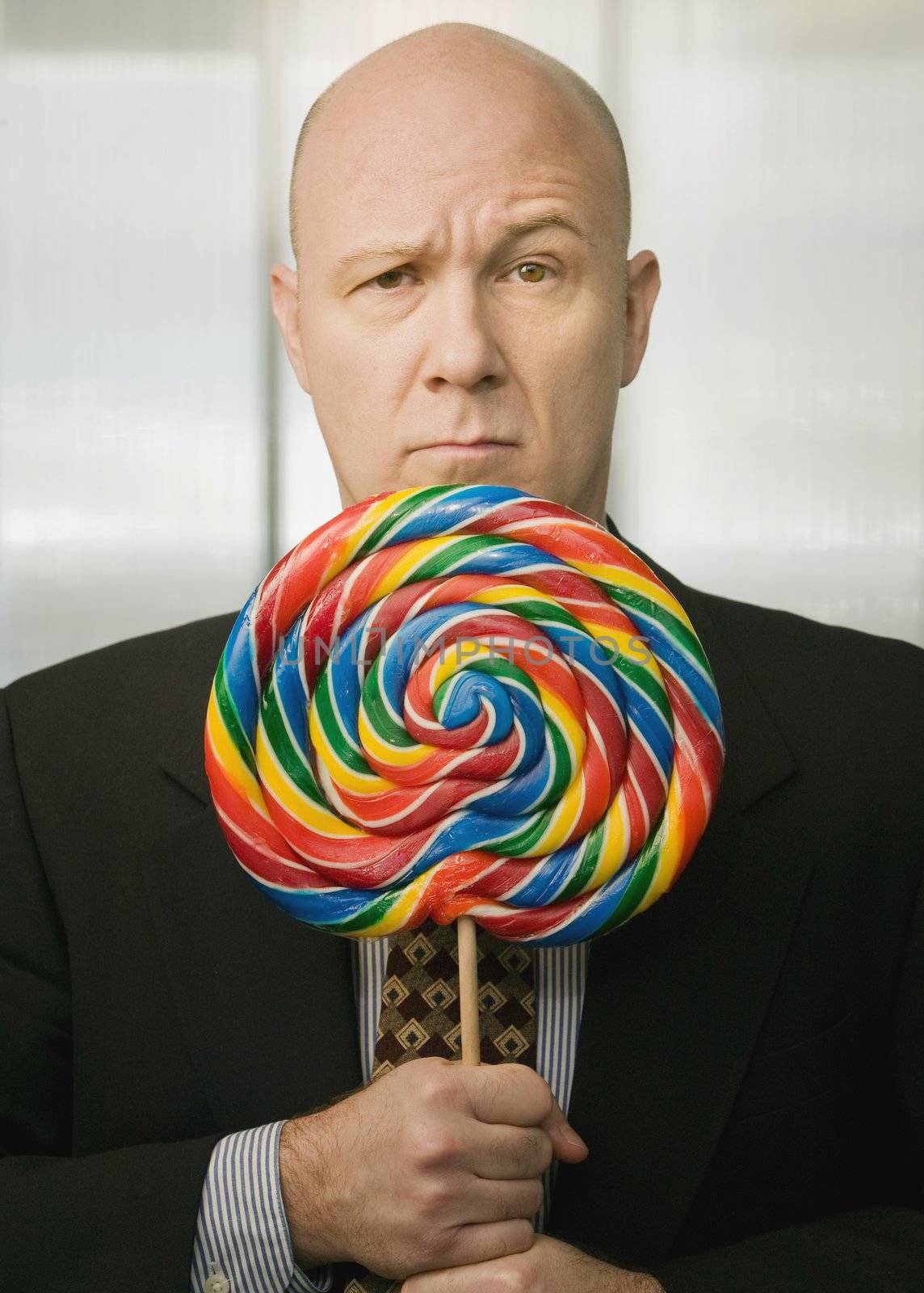 Businessman portrait with a brightly colered big lollipop