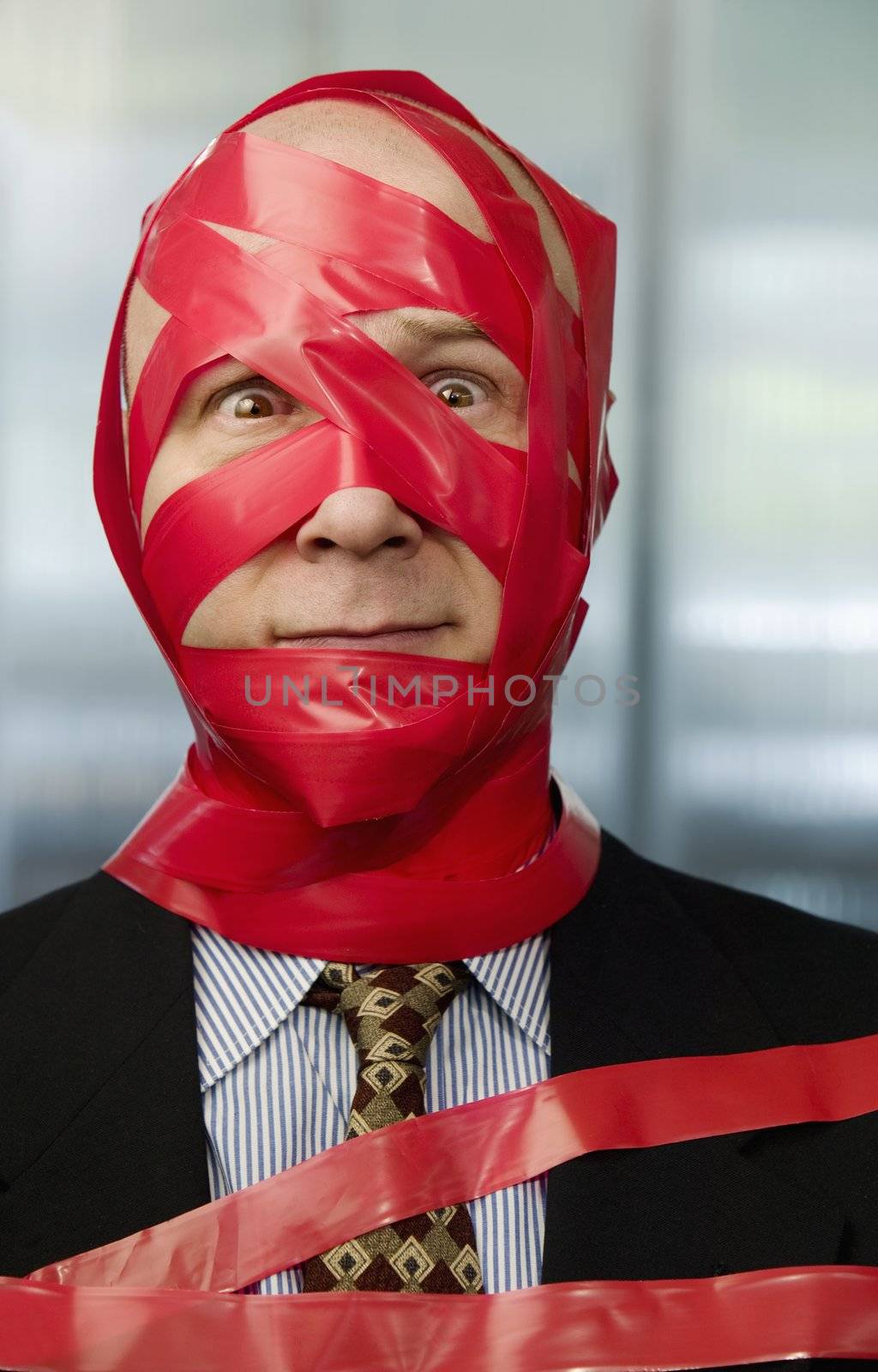 Businessman wrapped in red tape